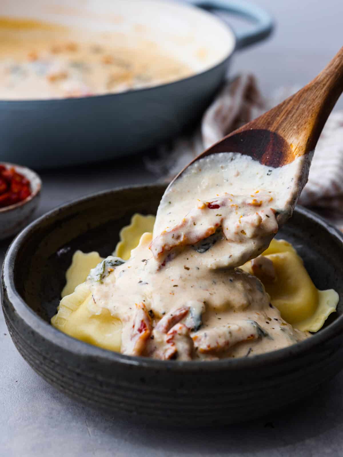 Creamy Tuscan garlic sauce is the secret weapon you didn't know your kitchen needed โ it makes all of your favorite meals unforgettable! It's the most amazing blend of sun-dried tomatoes, cream, garlic, parmesan, and tasty seasonings. Whether it's pasta, meat, or fish, this sauce does it all! Pouring sauce over ravioli.