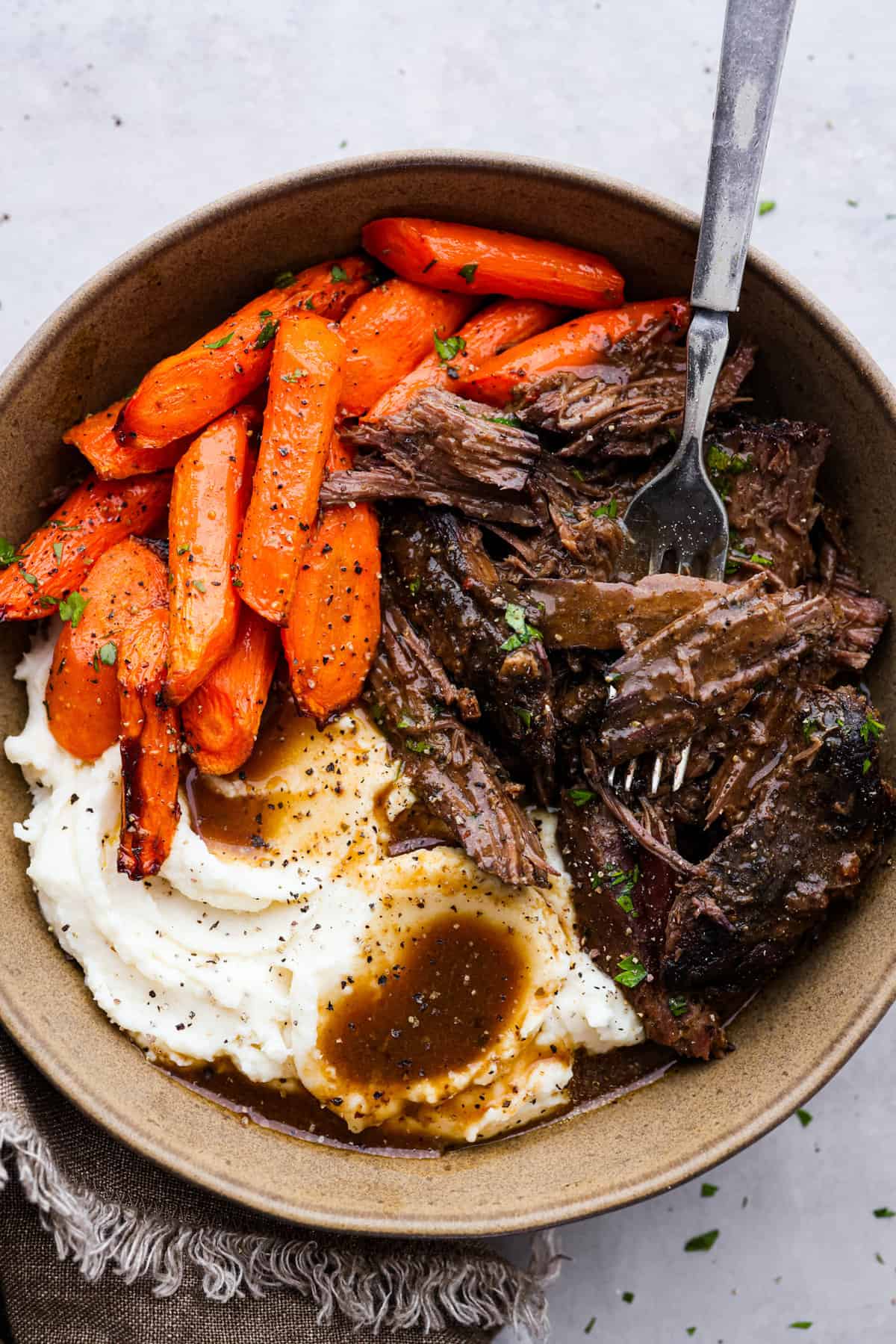 This 3 packet roast is my go-to for an easy but delicious Sunday dinner. Add brown gravy, Italian dressing, and ranch dressing powders to a slow cooker with your beef and then let it work its magic! It creates an ultra-tender, flavorful roast youโll love coming home to at the end of the day. Shredded pot roast served with carrots and mashed potatoes.