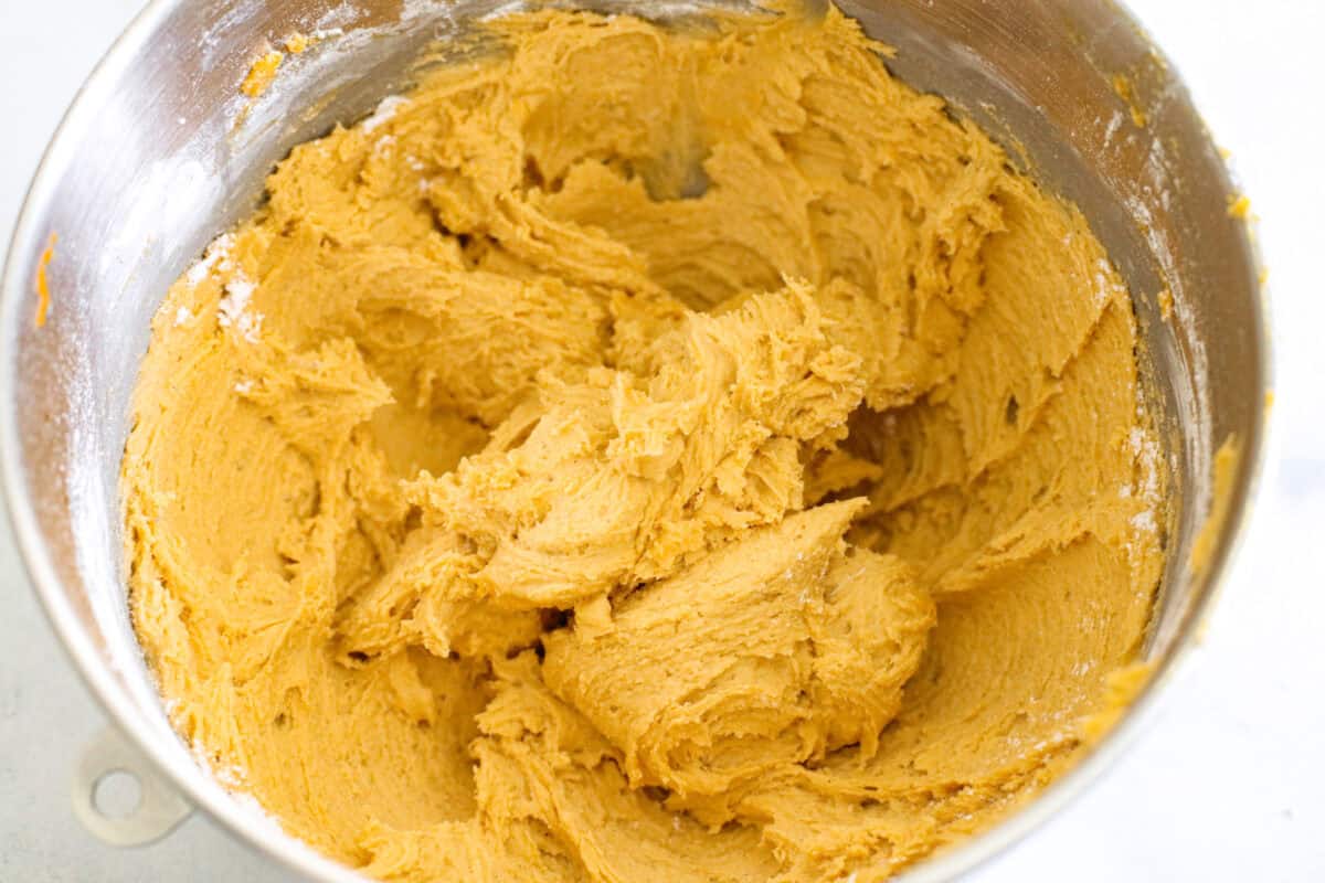 Pumpkin cheesecake snickerdoodles are a fresh take on a classic cookie! Delightfully soft and filled with tangy cream cheese, these cookies will be sure to get a "WOW!" from your friends and family! Pumpkin cookie dough in a bowl.