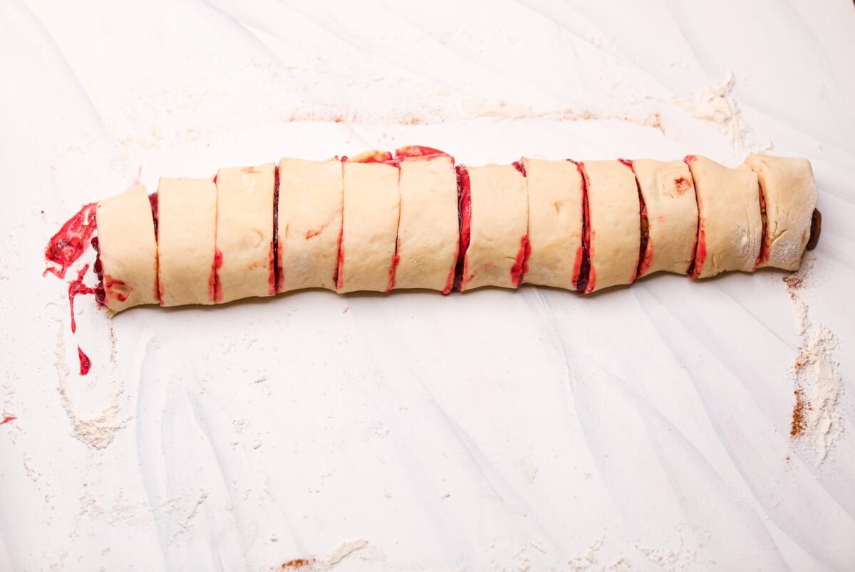 Strawberry cinnamon rolls are going to become a tradition in your house after you make these! The secret is the freeze-dried strawberries mixed with the lemon zest in the glaze - the flavor is to die for! Dough log rolled up and cut into sliced, unbaked strawberry cinnamon rolls.