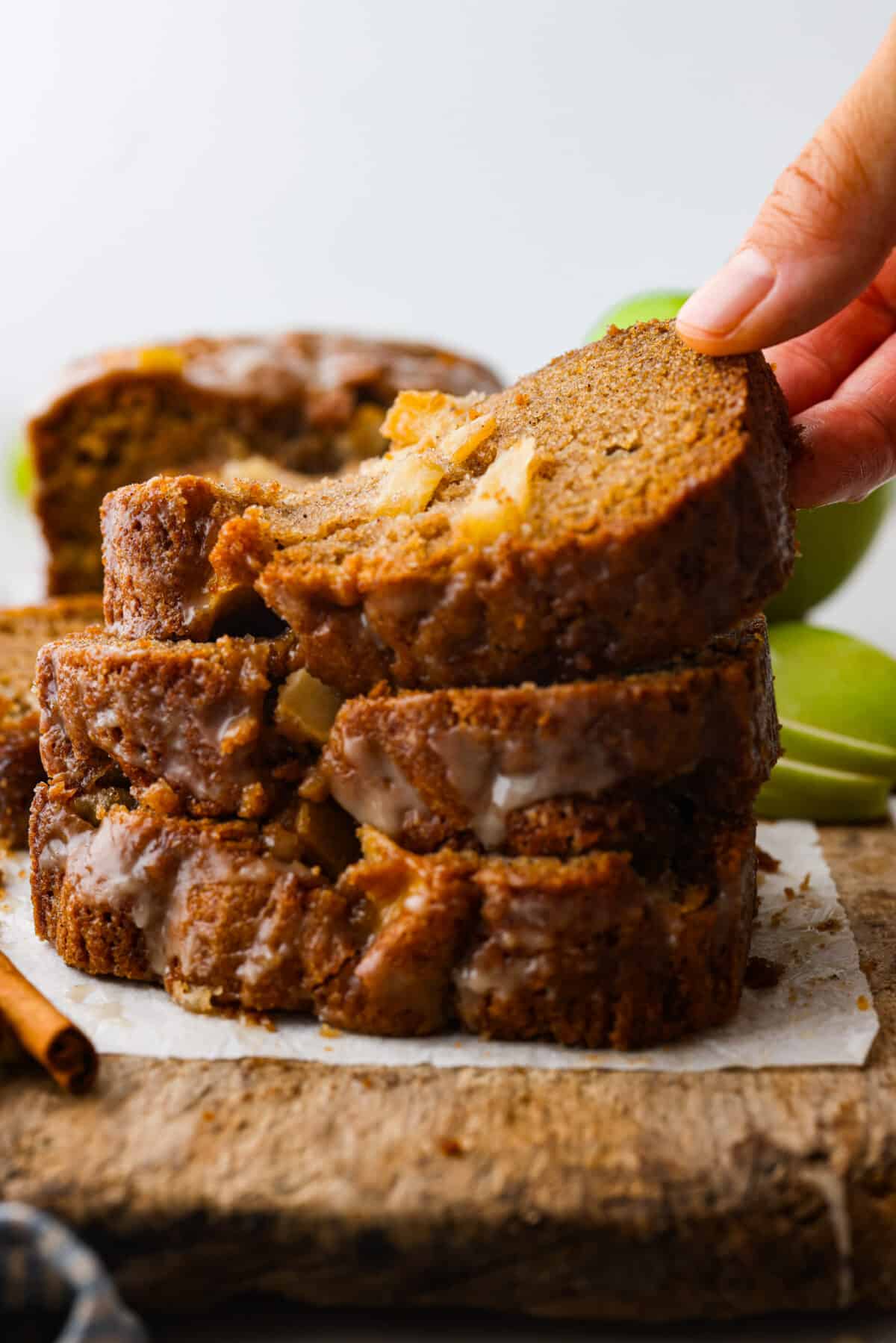 This deliciously sweet apple bread with hints of seasonal spices is a the perfect fall dessert. Each bite is packed with chunks of apple and hints of cinnamon and vanilla. Make this your new fall favorite indulgence. 3 slices of apple bread stacked on top of each other, and one being picked up.