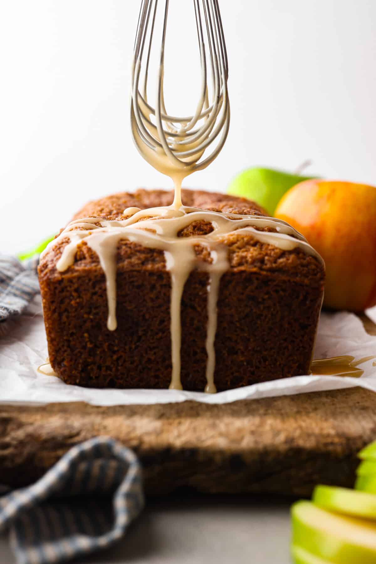 This deliciously sweet apple bread with hints of seasonal spices is a the perfect fall dessert. Each bite is packed with chunks of apple and hints of cinnamon and vanilla. Make this your new fall favorite indulgence. Front view of apple bread, topped with a sweet glaze.