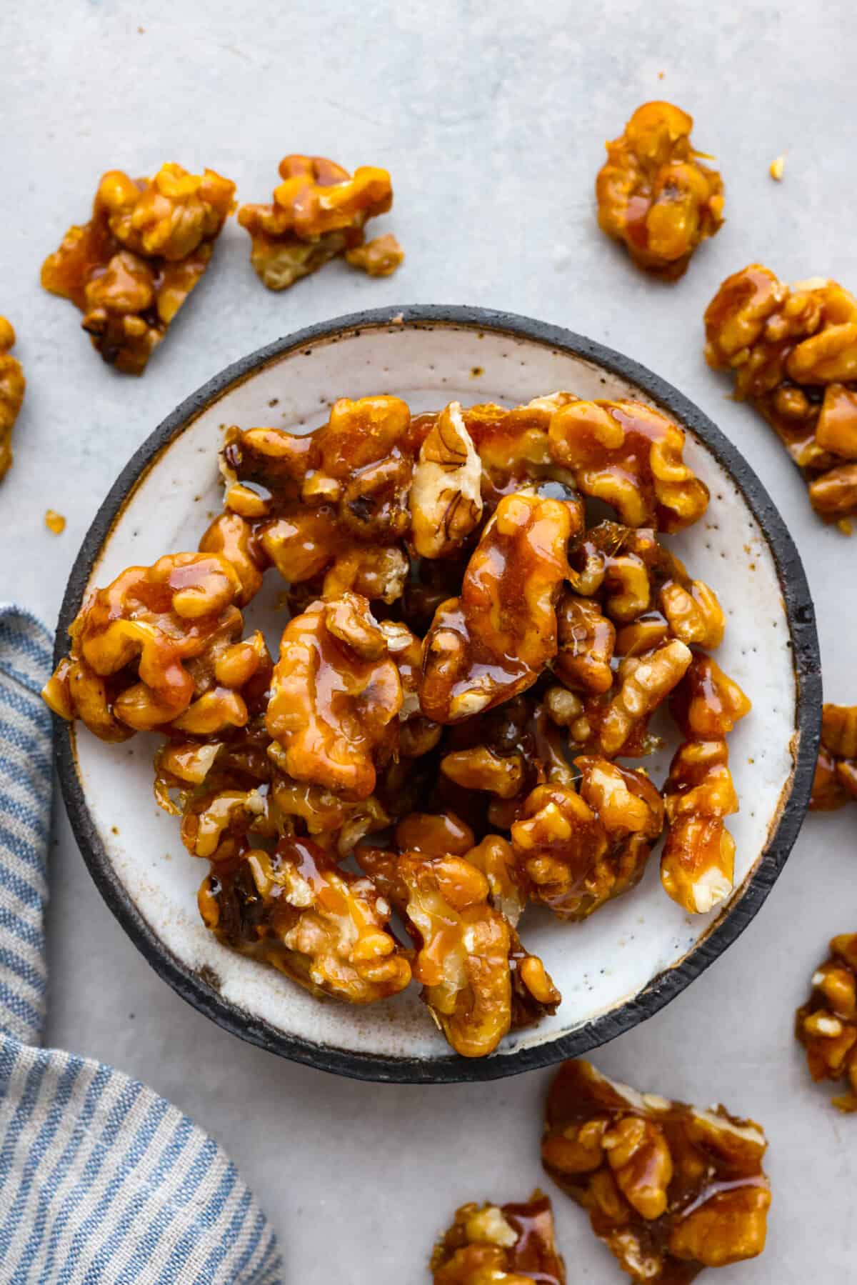 Elevate your food with these easy Candied Walnuts. With just sugar and walnut halves, these are a sweet and crunchy treat perfect for salads, desserts, or on their own as a delicious snack! The top view of a bowl of candied walnuts.