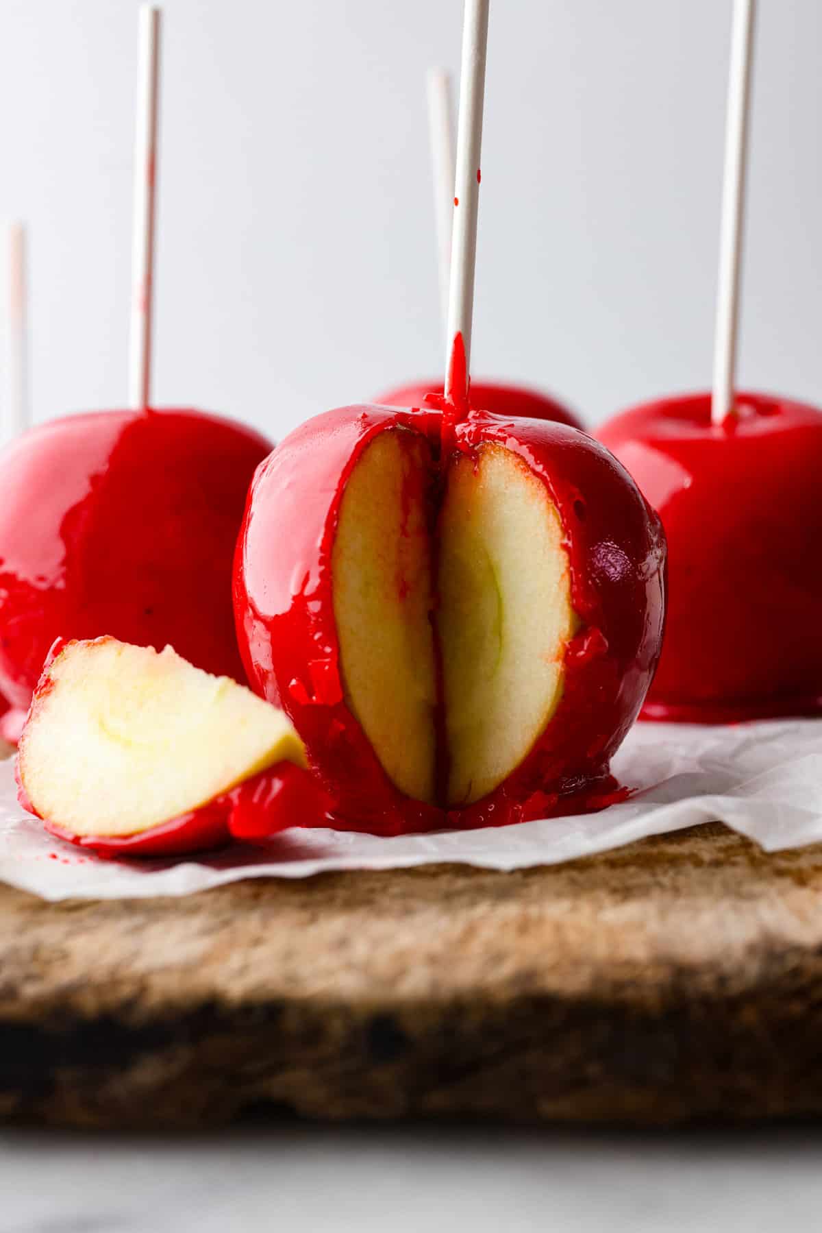 Fall is here, and that means itโs time to make a tasty batch of candy apples! Your favorite crisp apples coated in a glossy, red sugar mixture that almost looks too good to eat! Hero image of candied apples, one has a piece cut out of it.