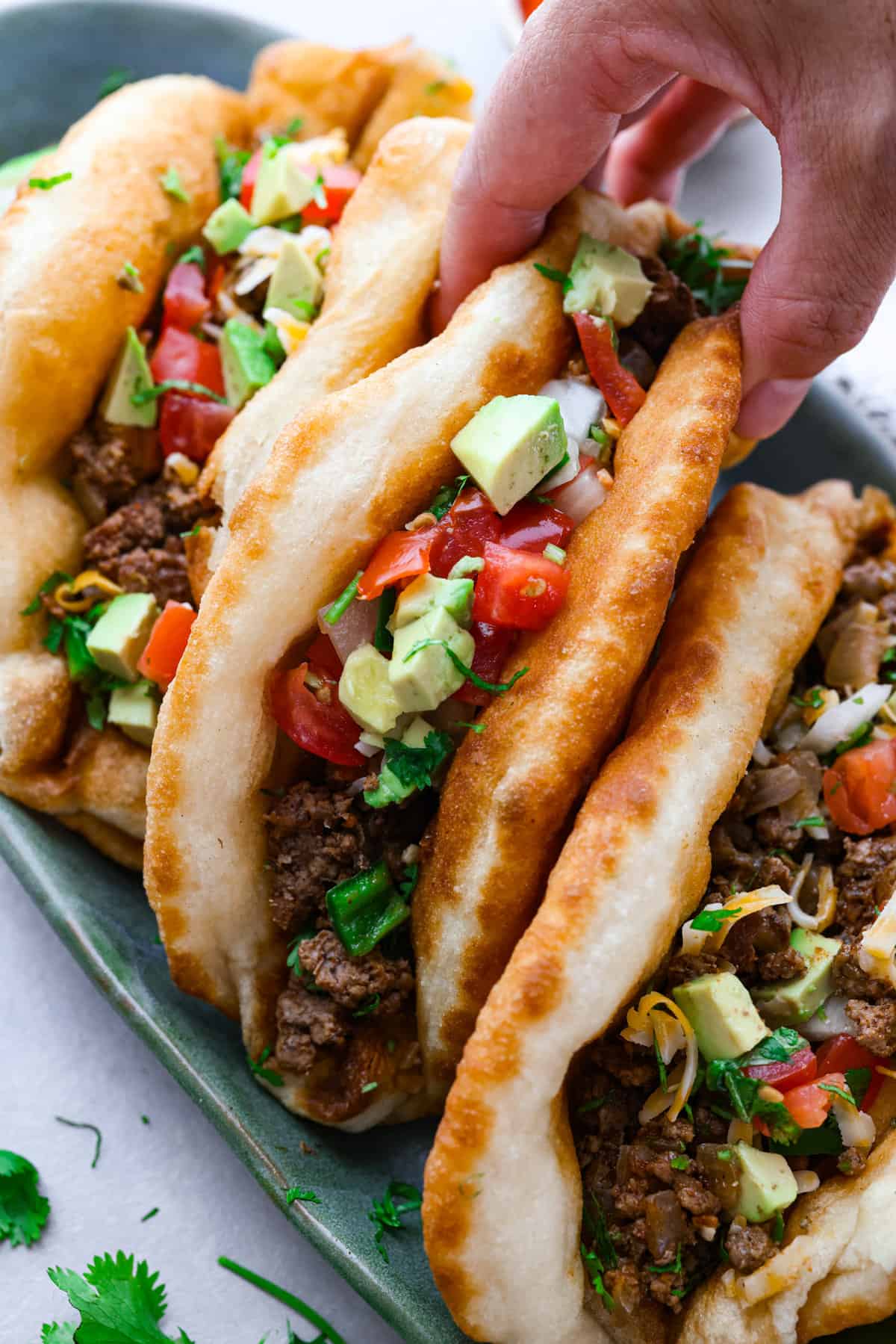 All your favorite taco fixings inside a warm, fluffy piece of fried bread! Homemade chalupas are a knockout dinner the whole family will go crazy over. A chalupa being picked up.