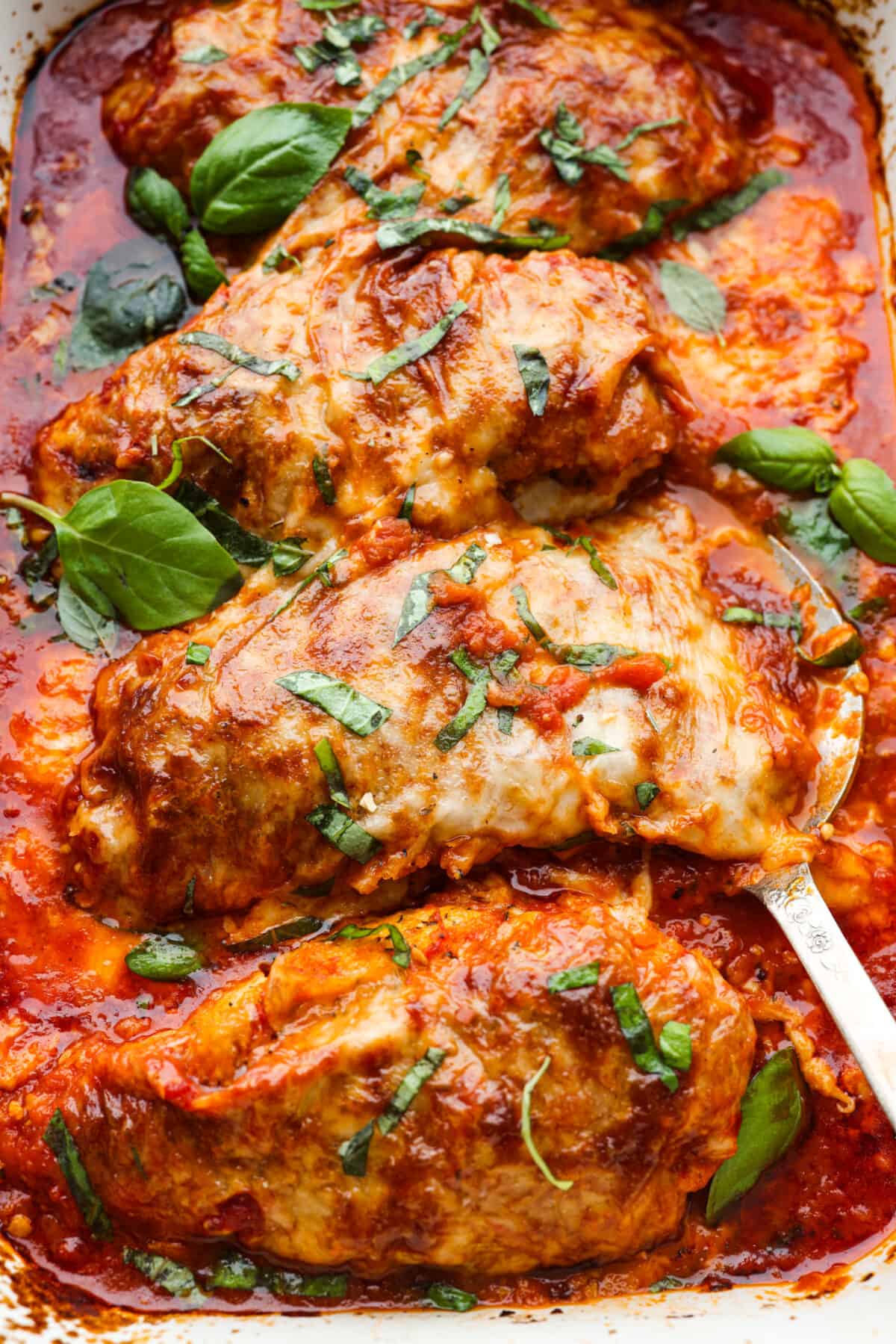 Herb-crusted chicken breasts coated in mozzarella, parmesan, and Italian seasoning, all smothered in homemade marinara sauce. Baked chicken marinara is simple, comforting, and oh-so-delicious! Closeup of chicken marinara.