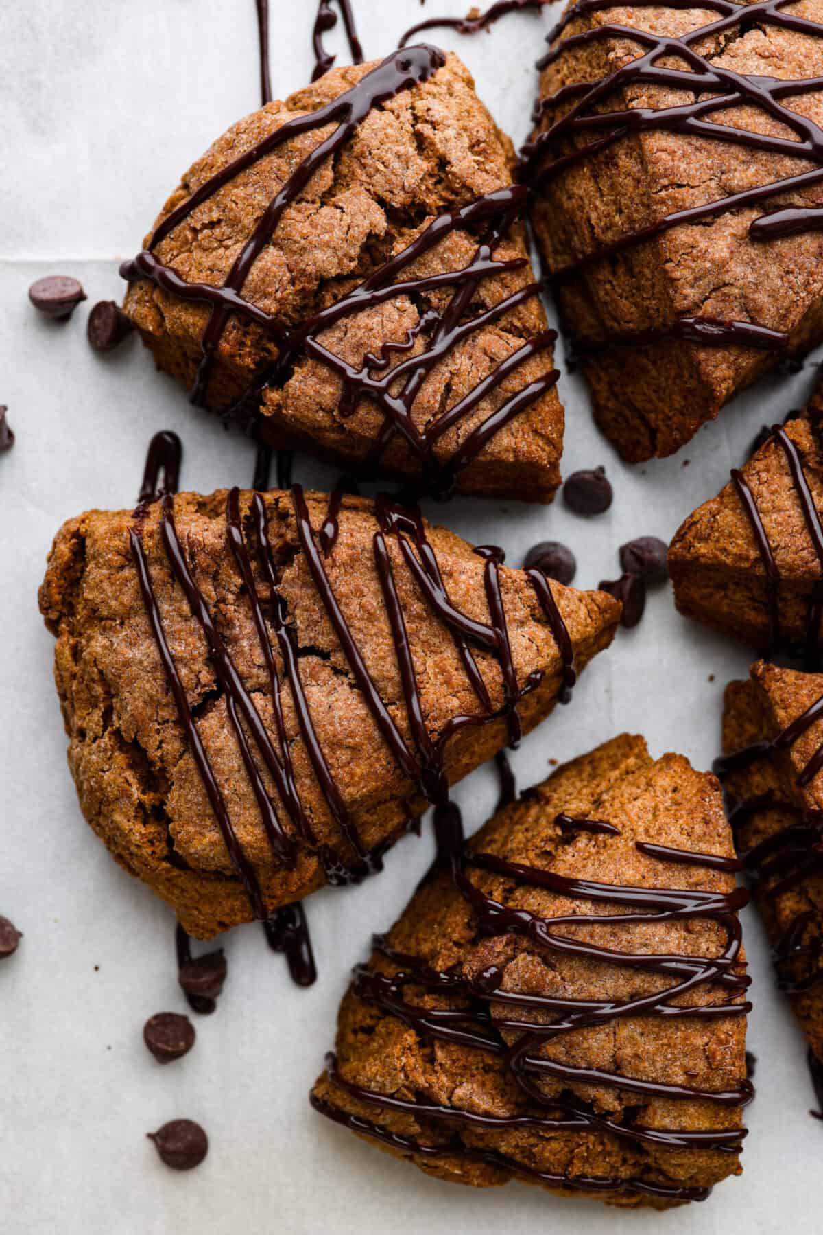 Soft, flaky, and drizzled with chocolate ganache, these homemade chocolate scones are the ultimate breakfast indulgence! Perfect for having alongside your morning coffee. Top-down view of 6 scones, arranged in a circle.