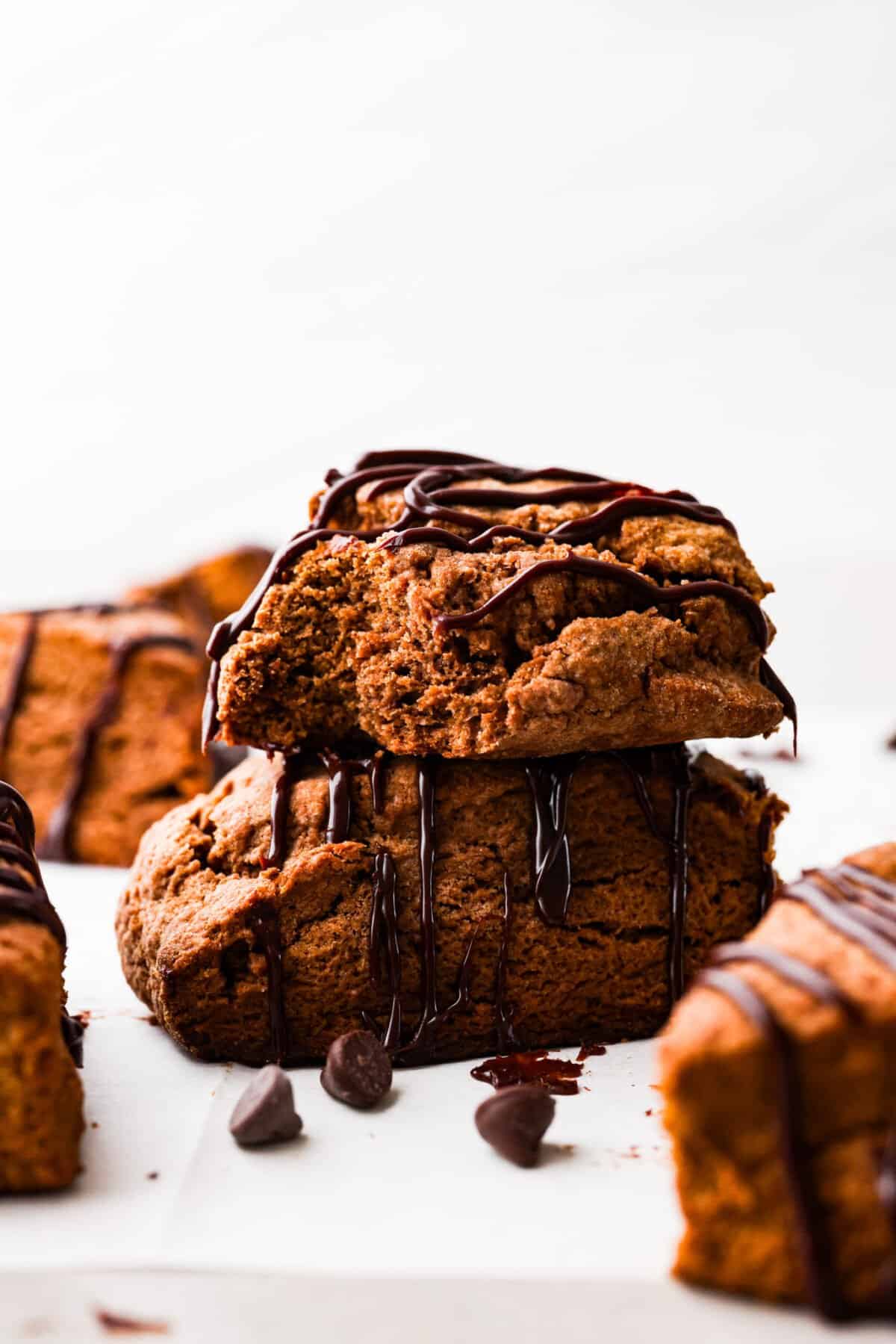 Soft, flaky, and drizzled with chocolate ganache, these homemade chocolate scones are the ultimate breakfast indulgence! Perfect for having alongside your morning coffee. 2 chocolate scones stacked on top of each other.
