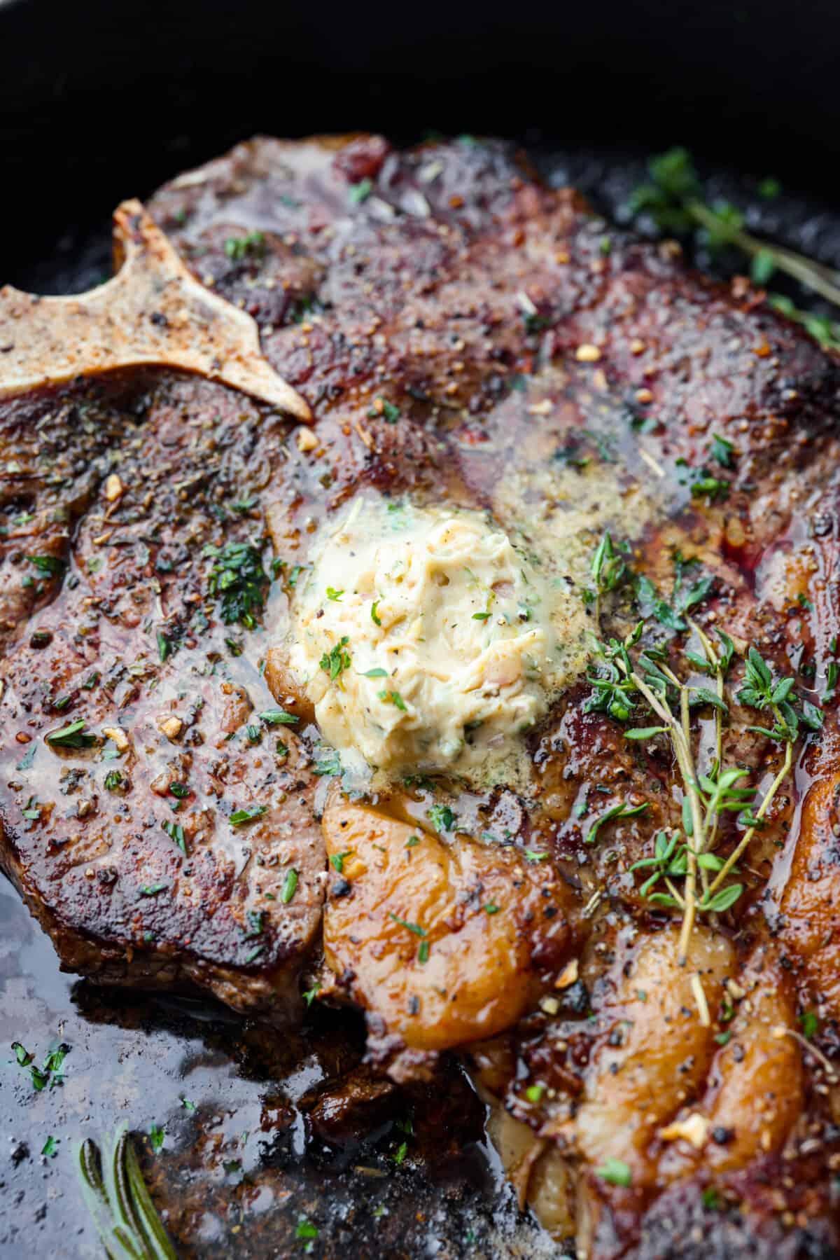 Anything smothered with this flavor-packed cowboy butter will satisfy your tastebuds! Soft butter mixed with garlic, shallot, fresh herbs, and seasonings that take your butter up a notch. Enjoy on top of meat, slathered on bread, or melted on a baked potato. Close view of cowboy butter melting on top of a cooked steak garnished with fresh herbs.