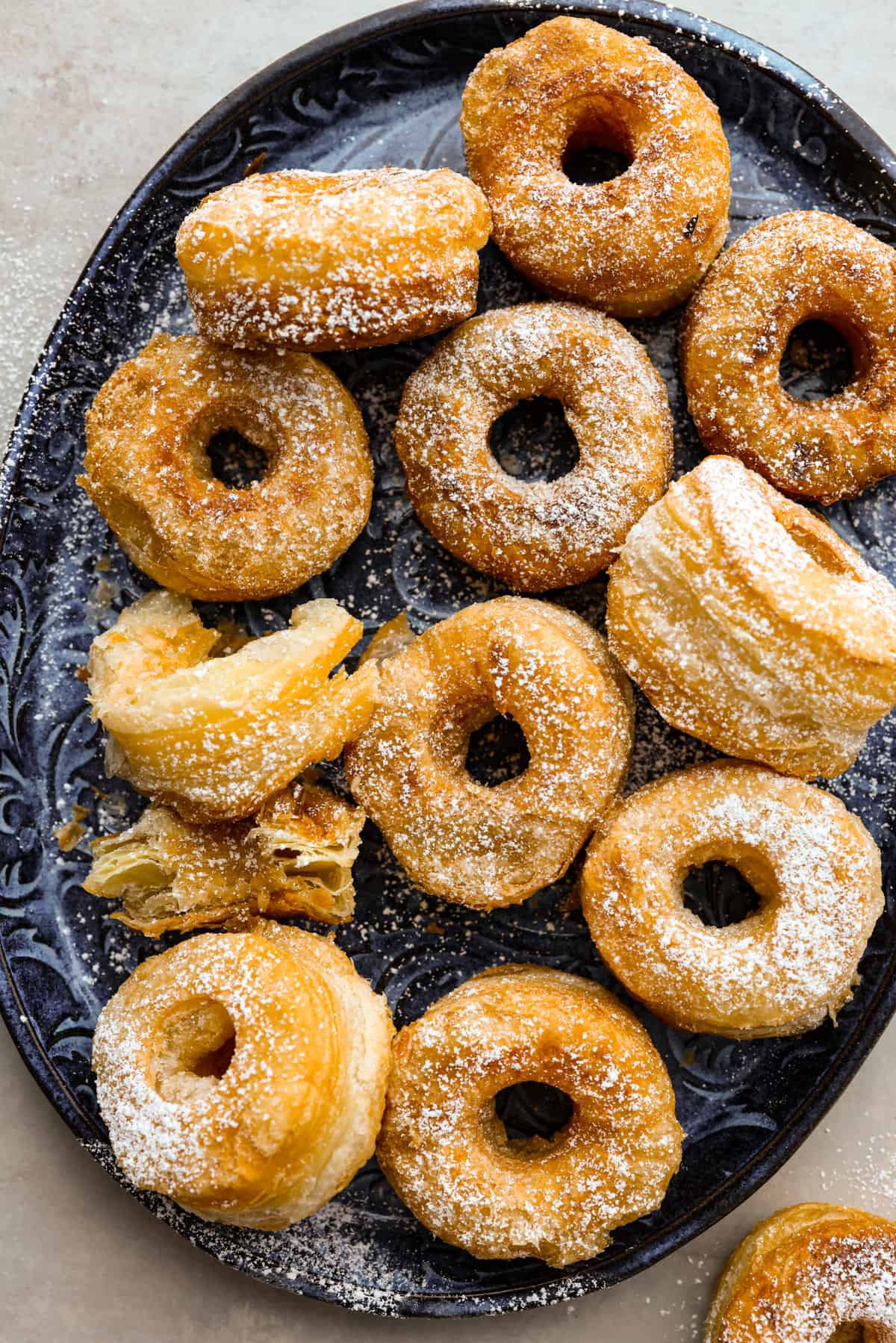 Get ready to discover the joy of homemade cronuts with this delicious recipe! Perfectly flakey and fried, this easy-to-make recipe is perfect for any occasion. The top view of a platter of cronuts.