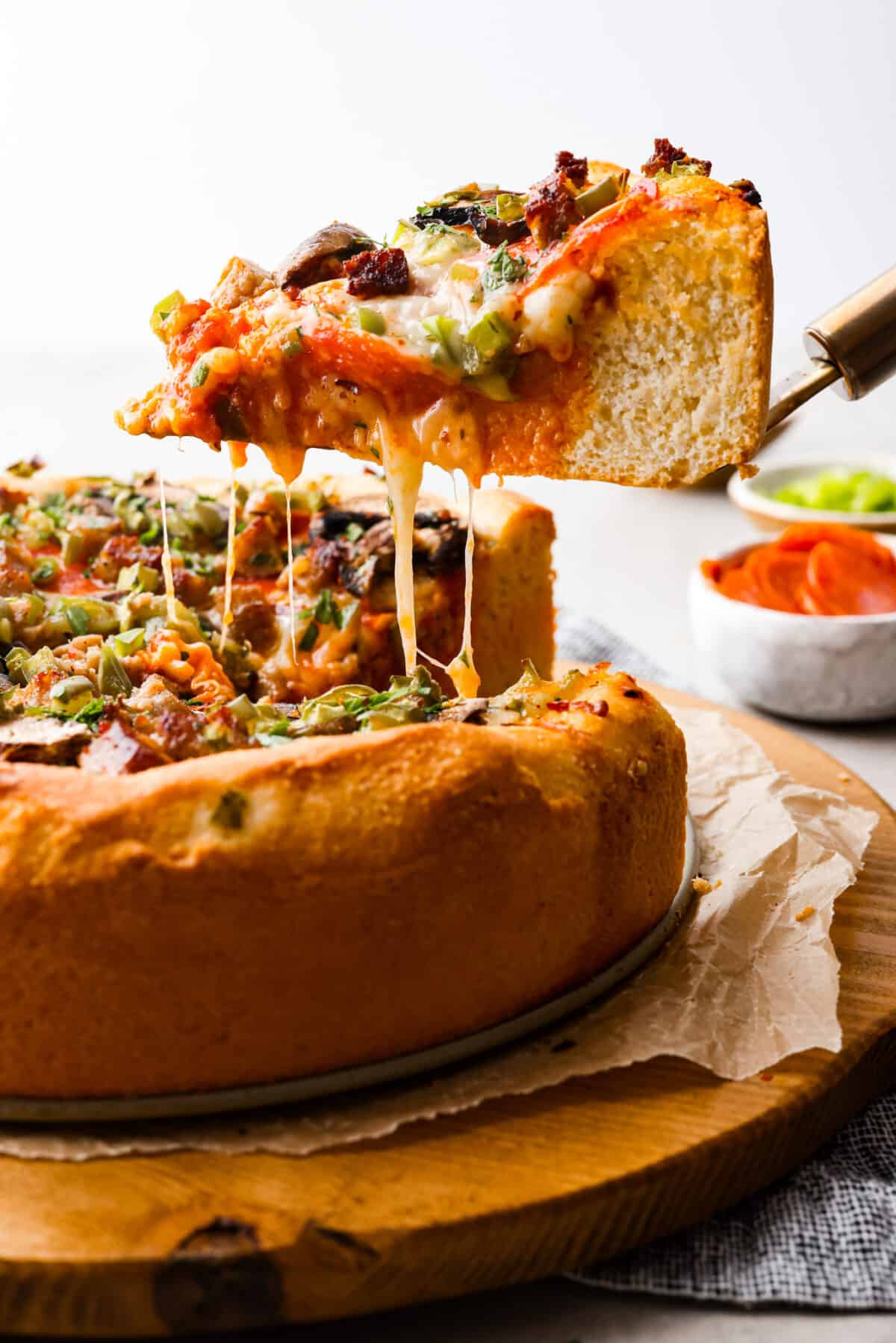 Authentic Chicago-style deep dish pizza! A thick, crispy and flaky crust topped with an easy homemade marinara sauce and shredded mozzarella cheese! It's comfort food at its finest and something the whole family will love. Picking up a slice of deep dish pizza.