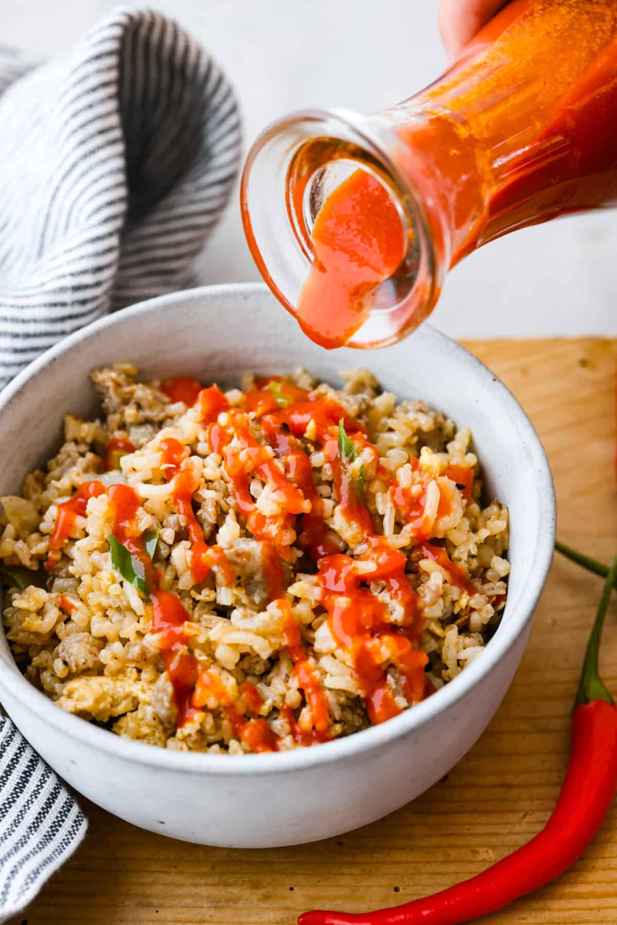 Sriracha sauce is a popular condiment that adds a burst of delicious spice to any dish. Try making it from scratch so it tastes just the way you like it! Adding a drizzle of sriracha to fried rice.