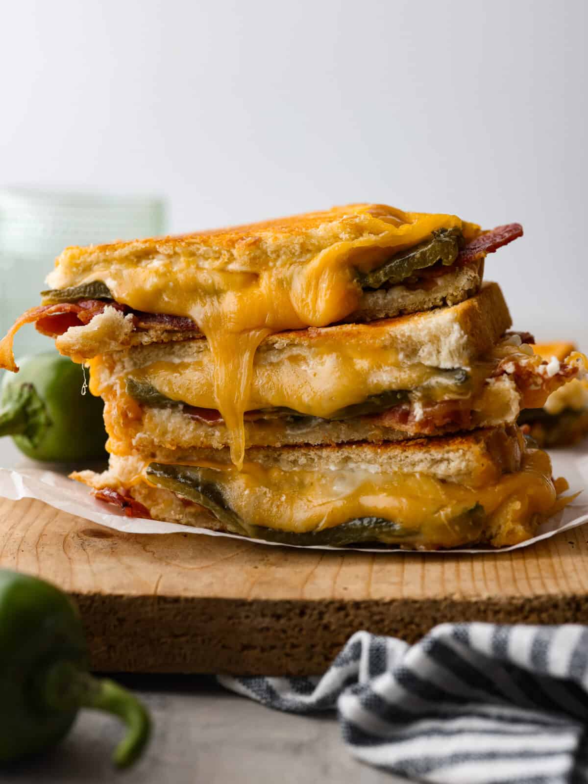 Add some kick to a classic comfort meal with this insanely good jalapeno popper grilled cheese! It's filled with melty colby jack, bacon, spicy jalapeños, and cream cheese to balance the heat and add creaminess. You're going to love it! 3 slices of jalapeno popper grilled cheeses stacked on top of each other.