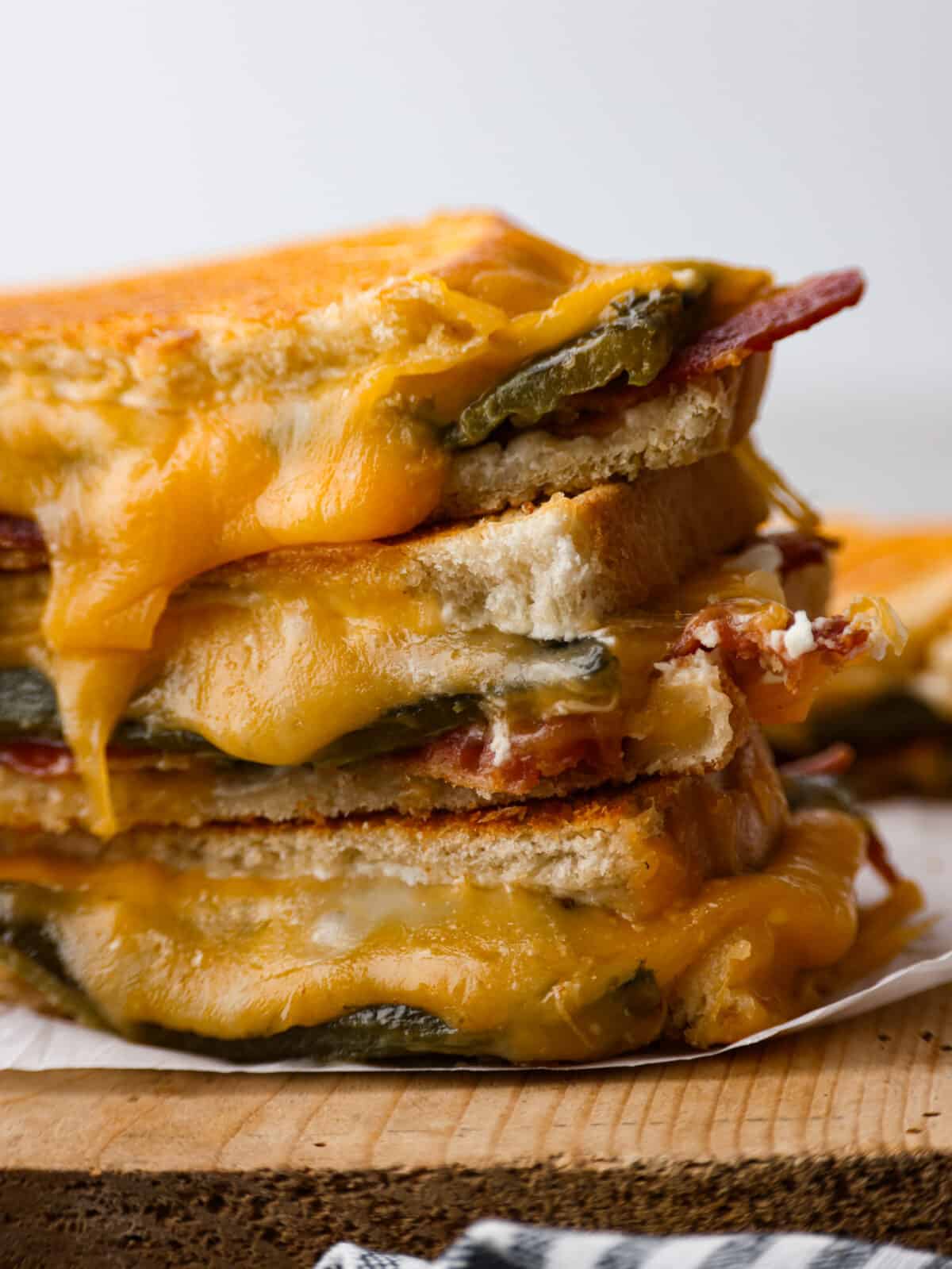 Add some kick to a classic comfort meal with this insanely good jalapeno popper grilled cheese! It's filled with melty colby jack, bacon, spicy jalapeños, and cream cheese to balance the heat and add creaminess. You're going to love it! Closeup of jalapeno popper grilled cheese sandwiches.