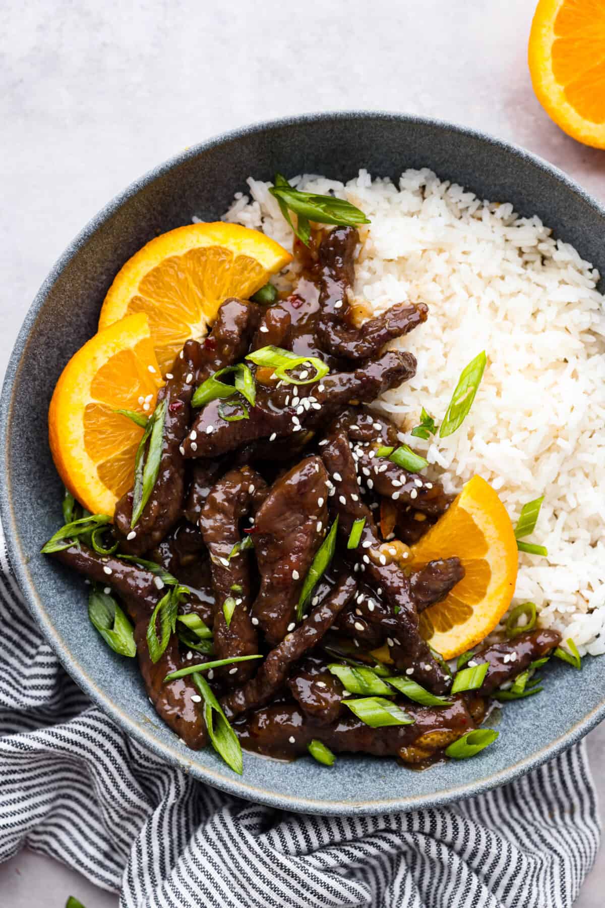 Crispy on the outside, tender on the inside beef strips coated in a tangy orange glaze. This orange beef recipe is the perfect weeknight dinner and sure to become a new family favorite! It may even rival your favorite takeout spot. Orange beef served over rice, garnished with orange slices.