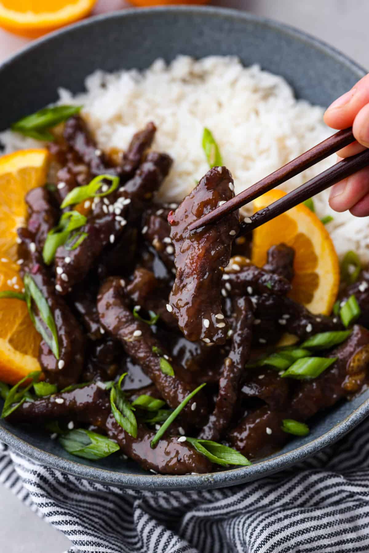 Crispy on the outside, tender on the inside beef strips coated in a tangy orange glaze. This orange beef recipe is the perfect weeknight dinner and sure to become a new family favorite! It may even rival your favorite takeout spot. Picking up a piece of beef with chopsticks.