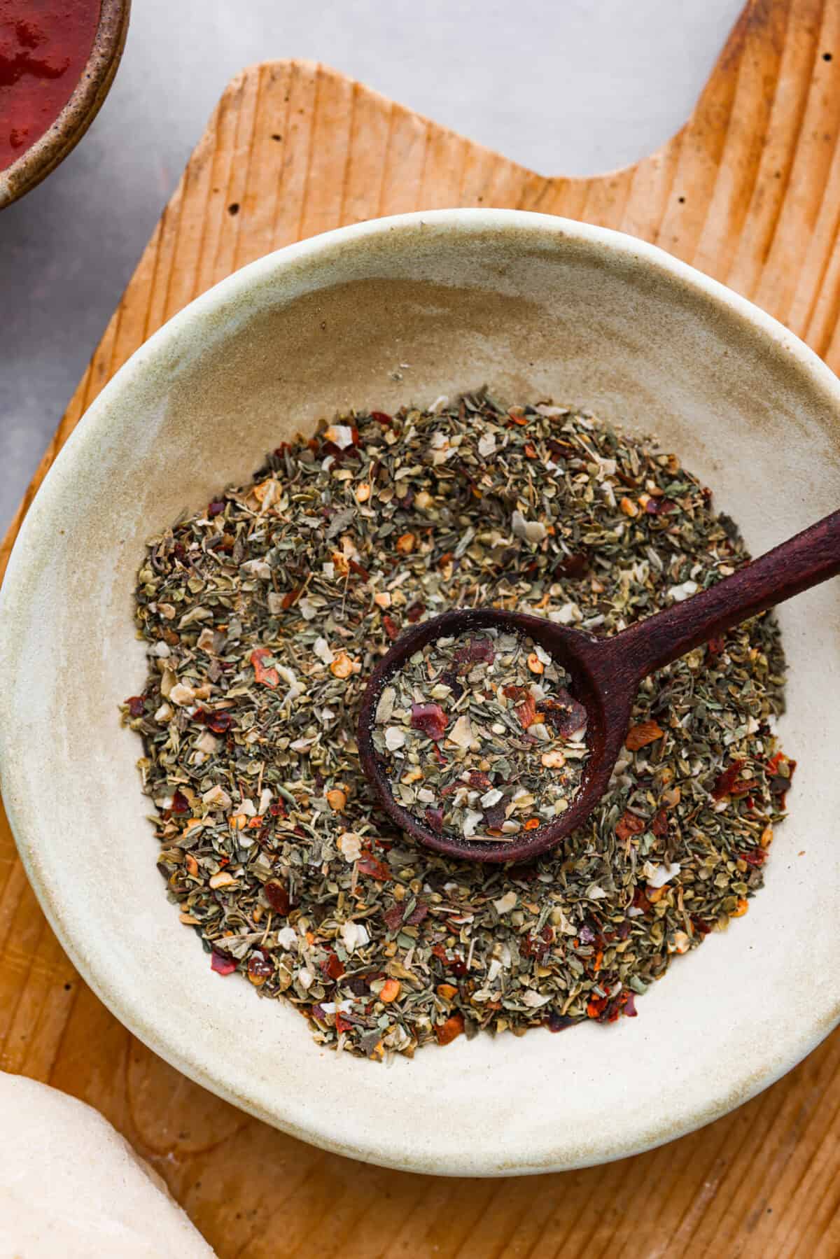 Add this homemade pizza seasoning to all of your favorite pizzas and watch them transform! It's the best blend of herbs, garlic, and red pepper flakes to make every bite a dream! Closeup of pizza seasoning.