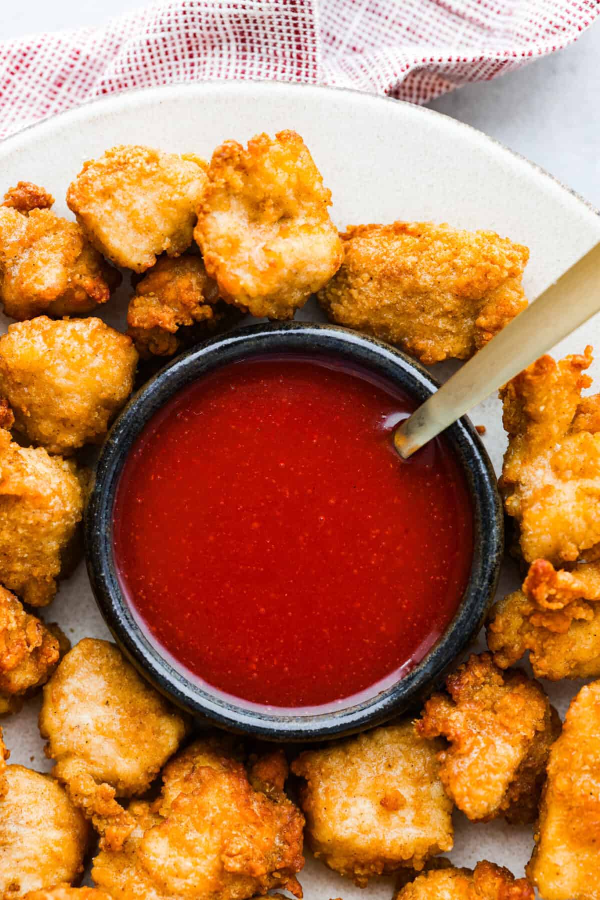 This copycat Chick-fil-A Polynesian sauce has the best kick of flavor! Itโs tangy, zesty, and sweet all at once. Grab some nuggets and get dipping! A bowl of polynesian sauce surrounded by chicken nuggets.