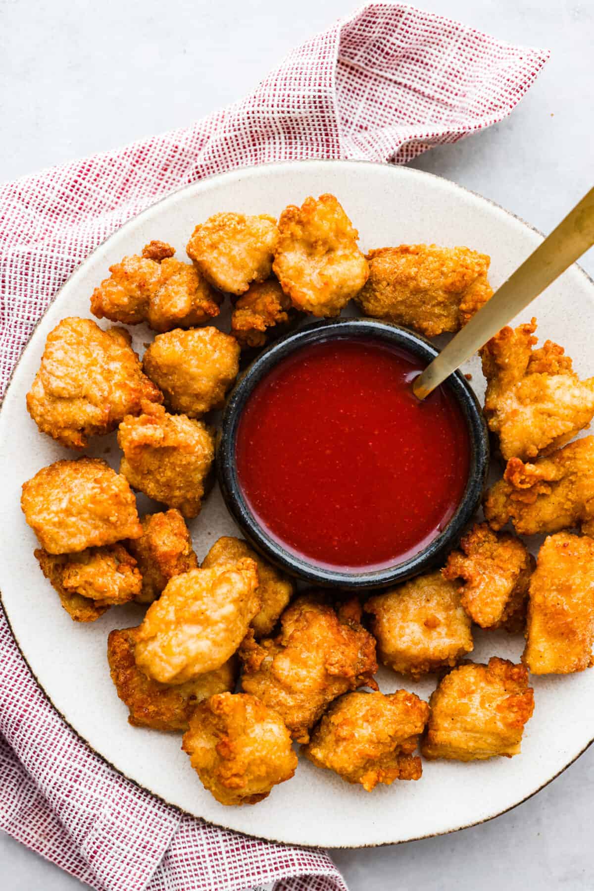 This copycat Chick-fil-A Polynesian sauce has the best kick of flavor! Itโs tangy, zesty, and sweet all at once. Grab some nuggets and get dipping! Top-down view of sauce and chicken nuggets on a white plate.