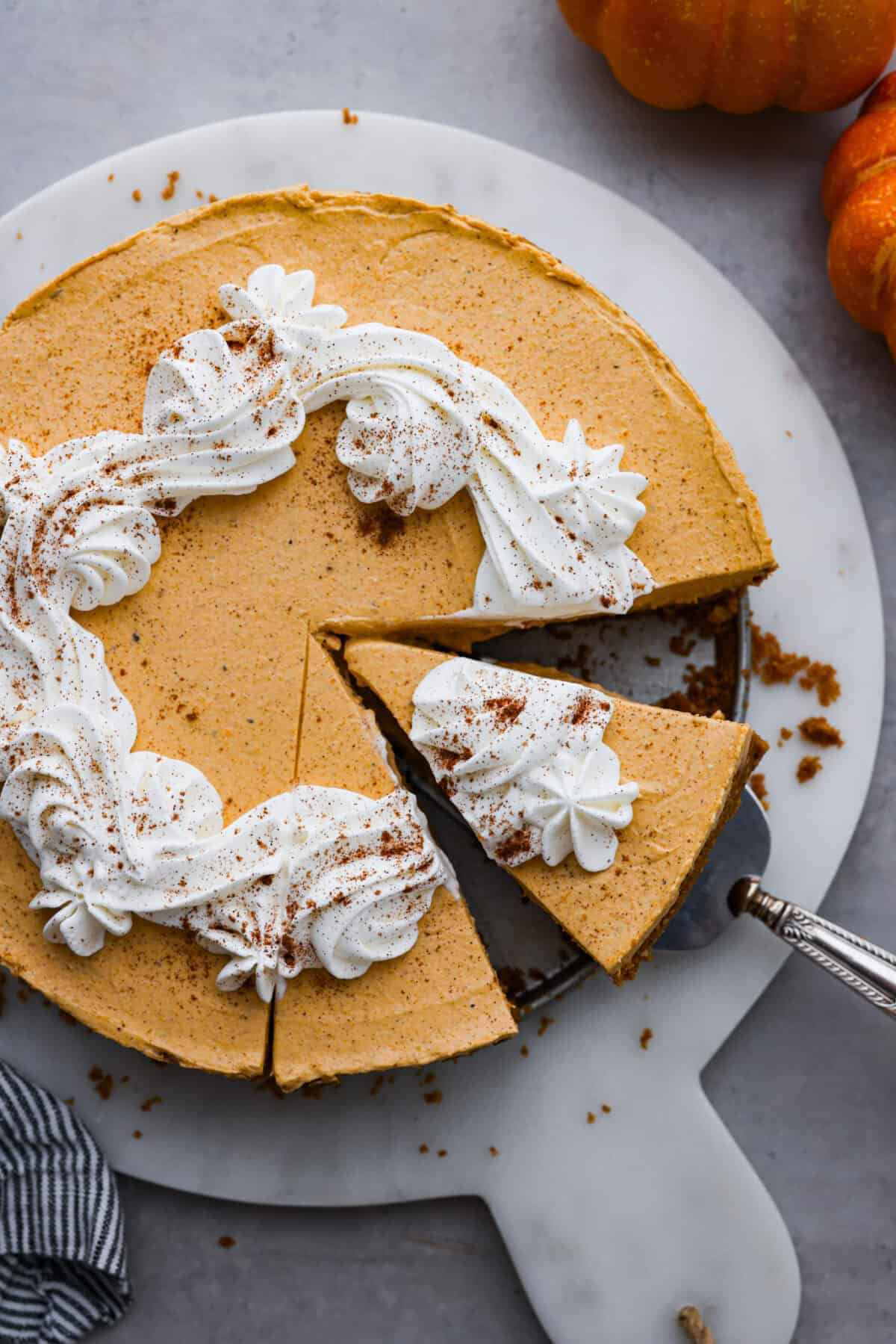 Delicious no-bake pumpkin cheesecake topped off with whipped cream is the perfect fall dessert. It has a creamy cheesecake filling with real pumpkin puree that sits in an irresistible Biscoff cookie crust.ย Itโs easy to make, rich and perfectly spiced! Overhead shot of no-bake pumpkin cheesecake.