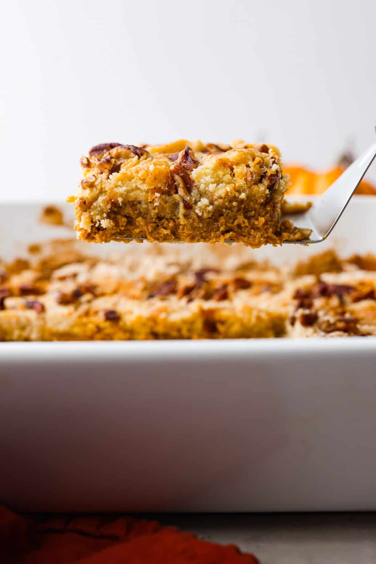 This pumpkin dump cake is a delicious fall favorite that combines the rich flavors of pumpkin, spices, and a cake mix. It's a mouthwatering treat that's incredibly easy to make! A piece of cake being served.