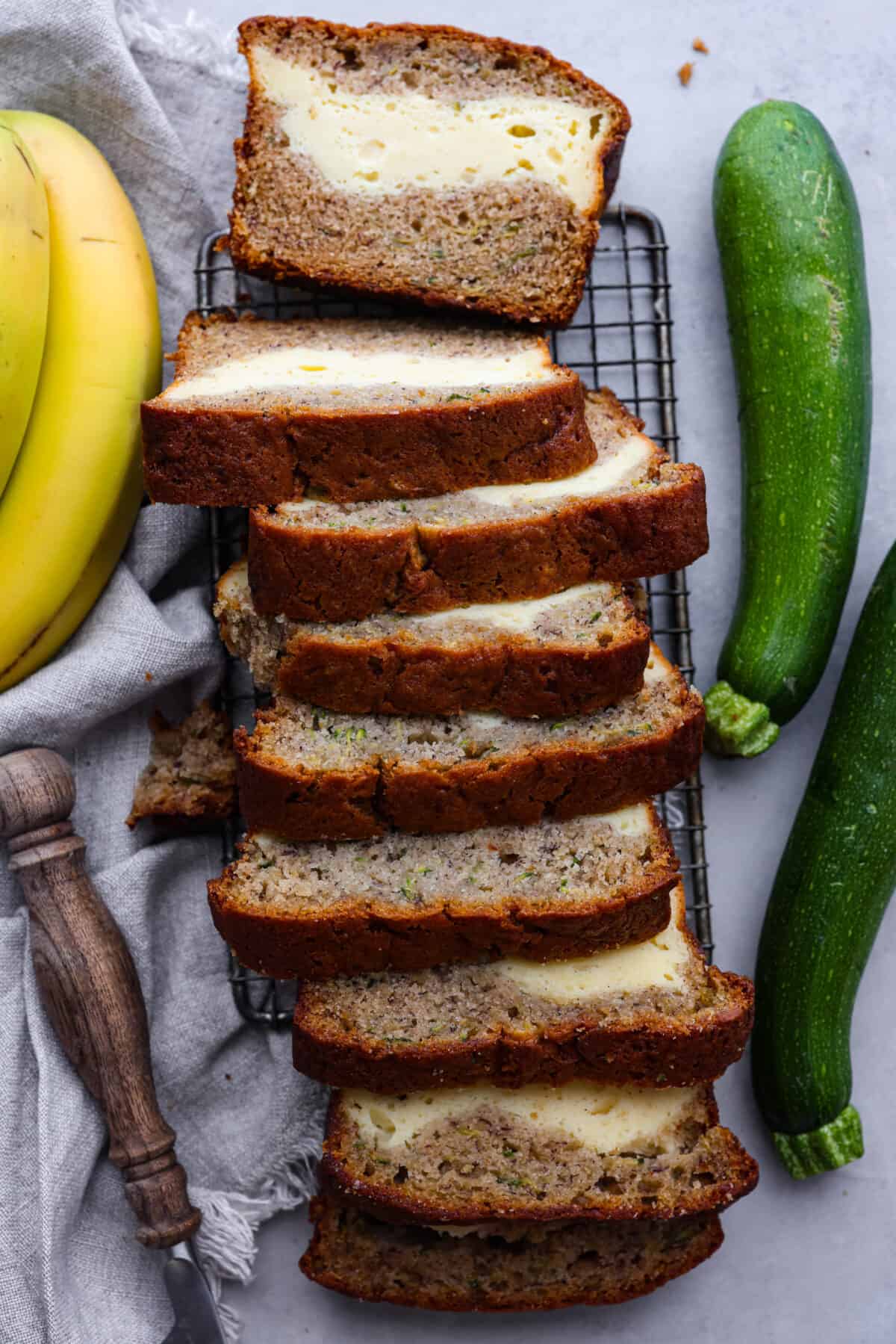 Overripe bananas and zucchini get used in this delicious and perfectly moist bread. The cream cheese swirl hidden inside is the best part! Enjoy a slice of cream cheese banana zucchini bread fresh out of the oven and thank me later. Top-down view of cream cheese banana zucchini bread.