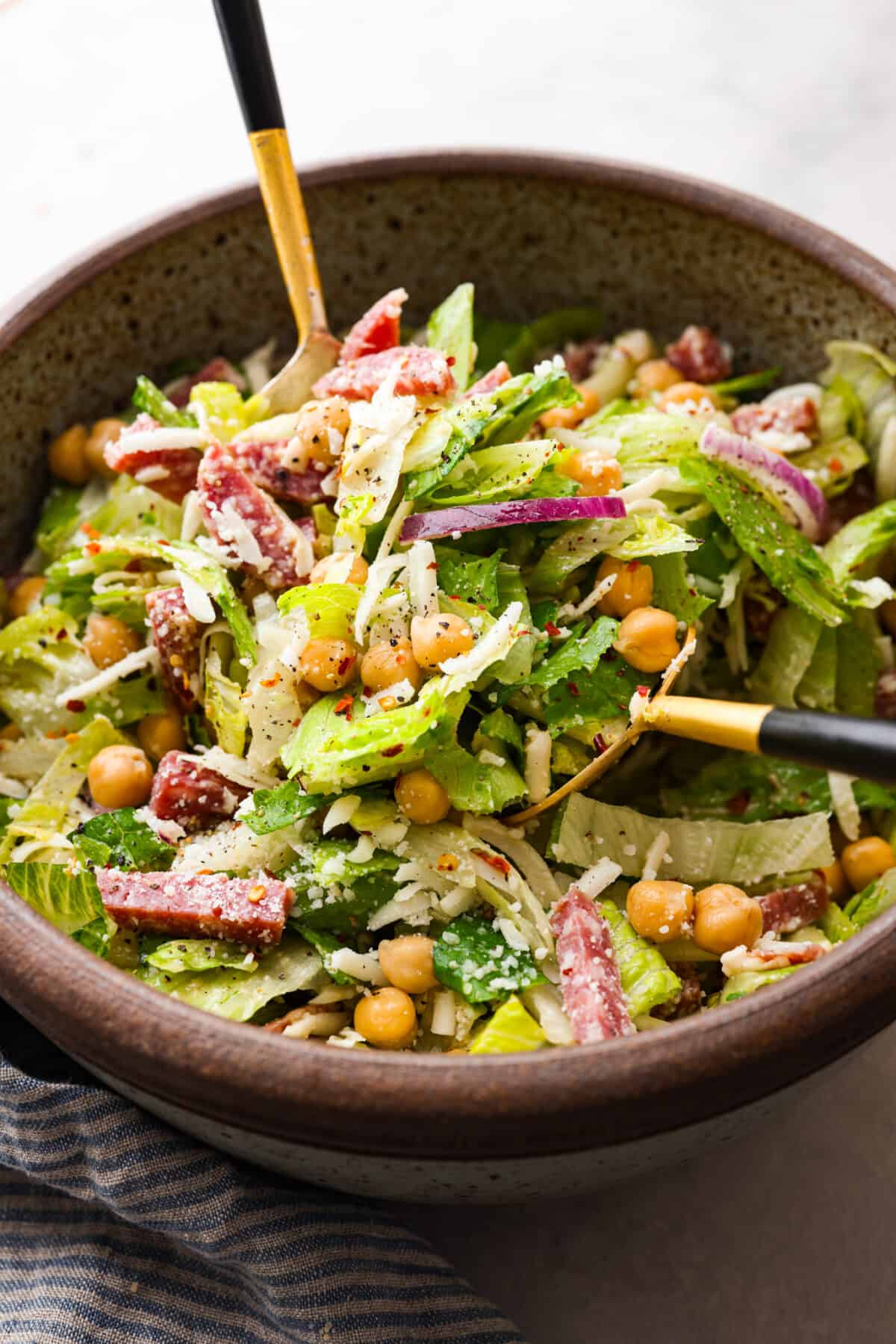 Fresh and flavorful, La Scala Salad is a copycat recipe of the famous Italian chopped salad served at La Scala restaurant in Beverly Hills. Rumor has it, Kim Kardashian orders this salad often, and for good reason! It's packed with delicious ingredients and crunchy texture, thanks to the chickpeas, salami, mozzarella cheese, and a zesty red wine vinaigrette. La Scala salad being mixed in a large bowl.