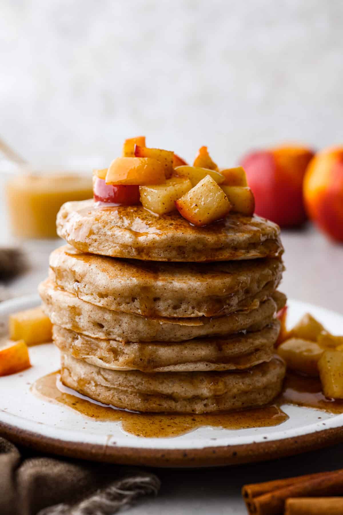 Fluffy applesauce pancakes are easy and delicious with a hint of brown sugar and cinnamon for a cozy fall flavor. The addition of applesauce gives these homemade pancakes the perfect texture. These will quickly become your favorite fall breakfast! Close view of applesauce pancakes with sauteed apples and syrup on top.