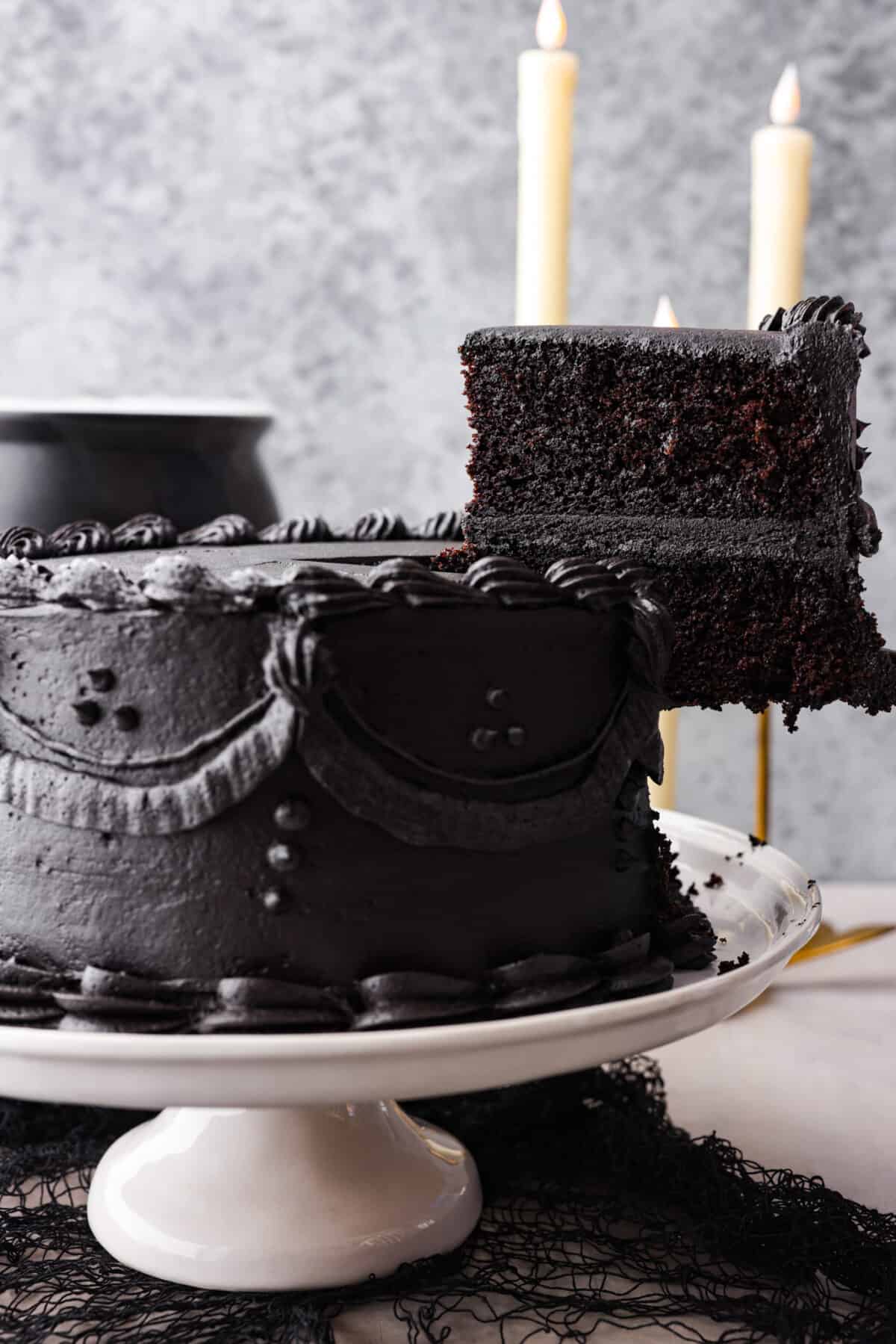 Come to the dark side with this gorgeous black velvet cake! Not only is it a showstopper and perfect for any Halloween party, but supremely moist and delicious to boot! Each bite is loaded with the most amazing cocoa flavor. Serving a slice of black velvet cake.