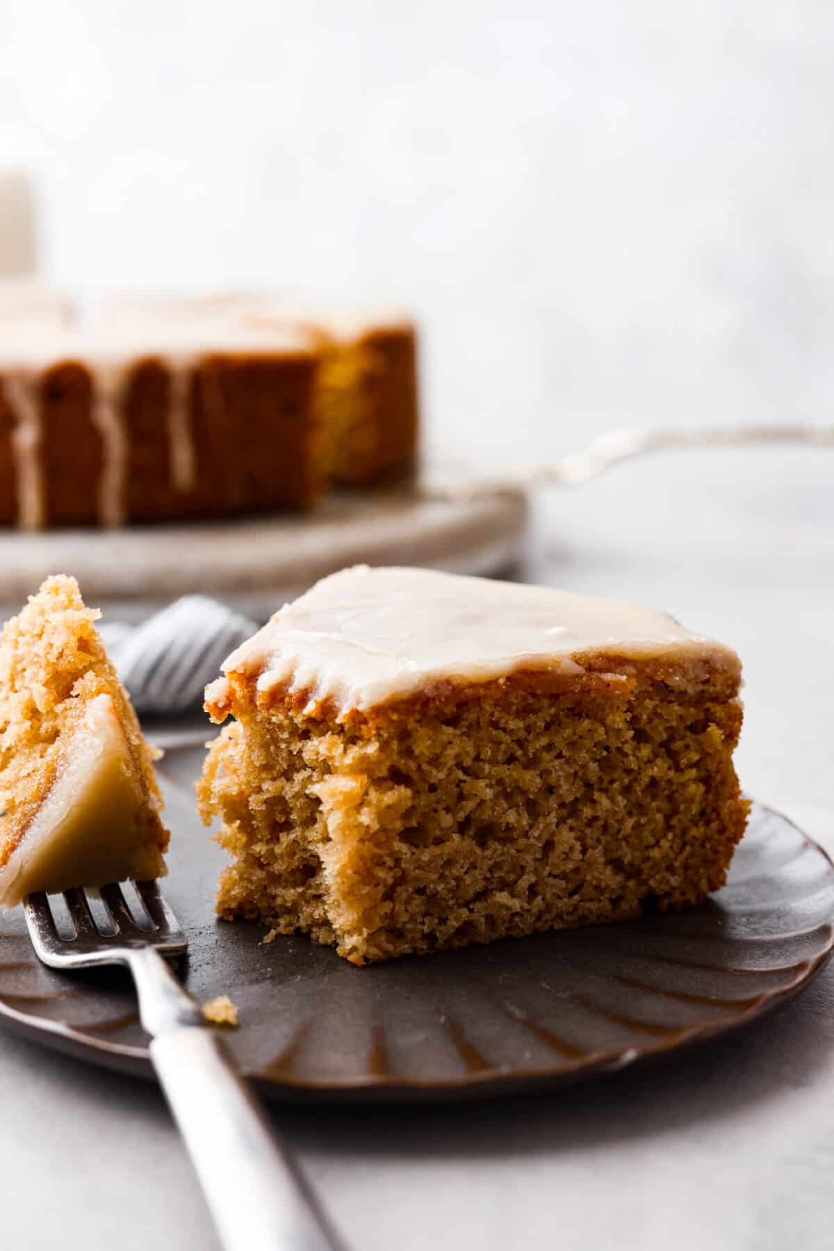 Comforting and delicious with an extra moist crumb, this Buttermilk Cake is the perfect dessert for any occasion!ย To make it really decadent, finish it off with an absolutely irresistible brown sugar vanilla glaze. Serve this at your next family gathering or potluck and watch the rave reviews come pouring in! A slice of cake with a bite taken out of it.