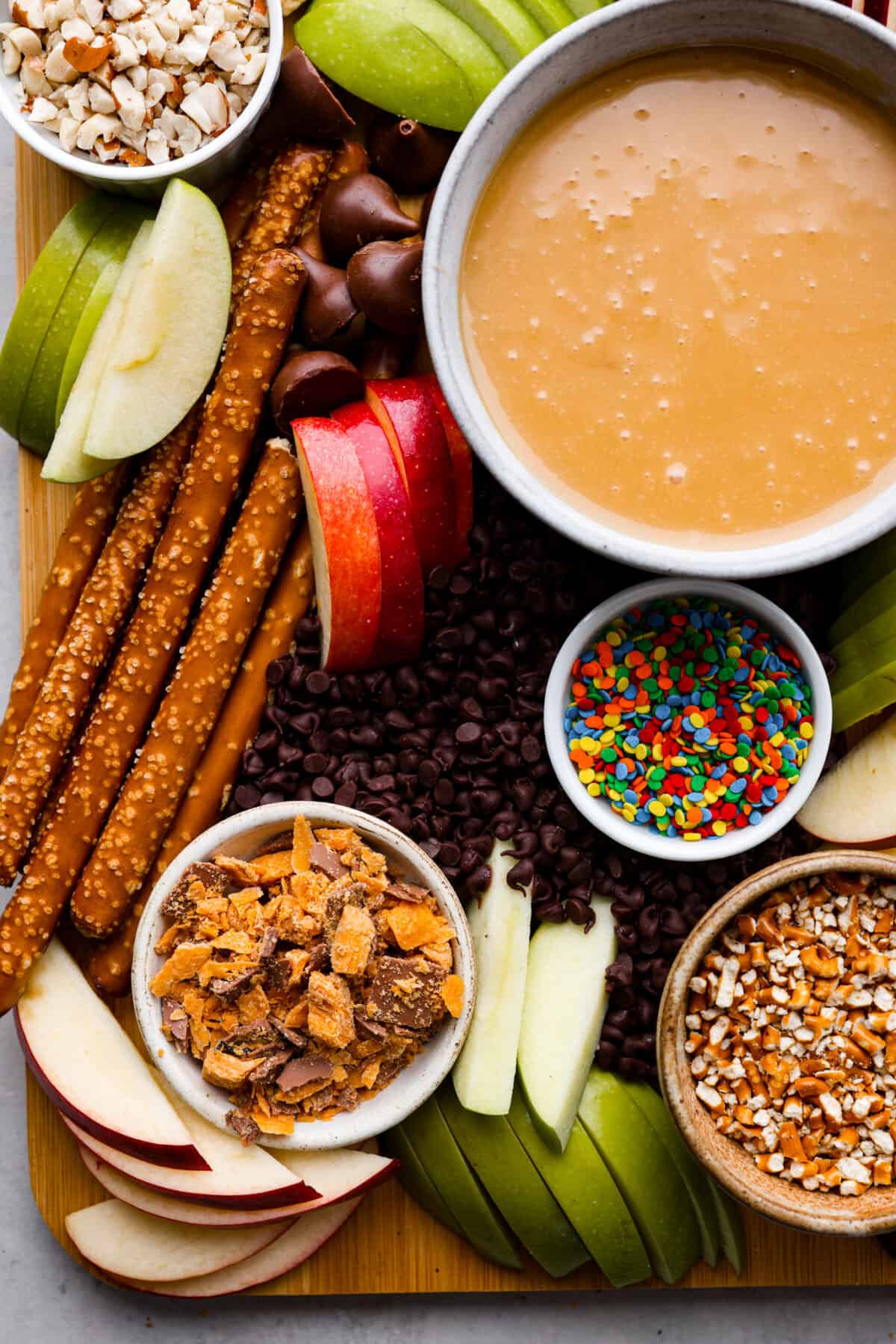 Everybody loves a good caramel apple, especially when they can customize it just the way they like! Make this caramel apple charcuterie board for your next fall party, I promise it will be a huge hit! It has a fun variety of toppings and things for dipping, so thereโs something for everyone! Pretzel rods for dipping as well as sprinkles, chocolate chips, and crushed heath bar pieces.