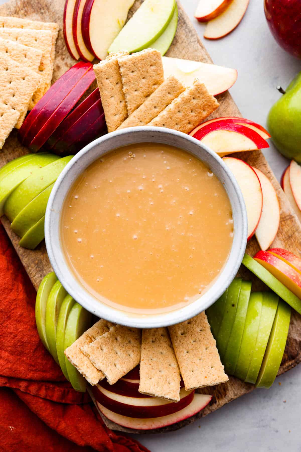 A classic fall treat made into a dip to share! In this caramel apple dip recipe, butter, caramels, and condensed milk get melted together to create the most indulgent treat. It's heavenly! A bowl of caramel apple dip served with sliced apples and graham crackers.