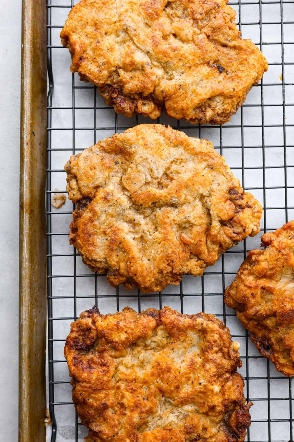 Chicken Fried Steak. The ultimate in Southern comfort food! Tender seasoned steak, coated in a thick batter and fried until golden brown with a creamy gravy drizzled on top. Simple, basic ingredients are all that is needed to bring this recipe to life in your own kitchen! Top-down view of chicken fried steaks on a wire rack.