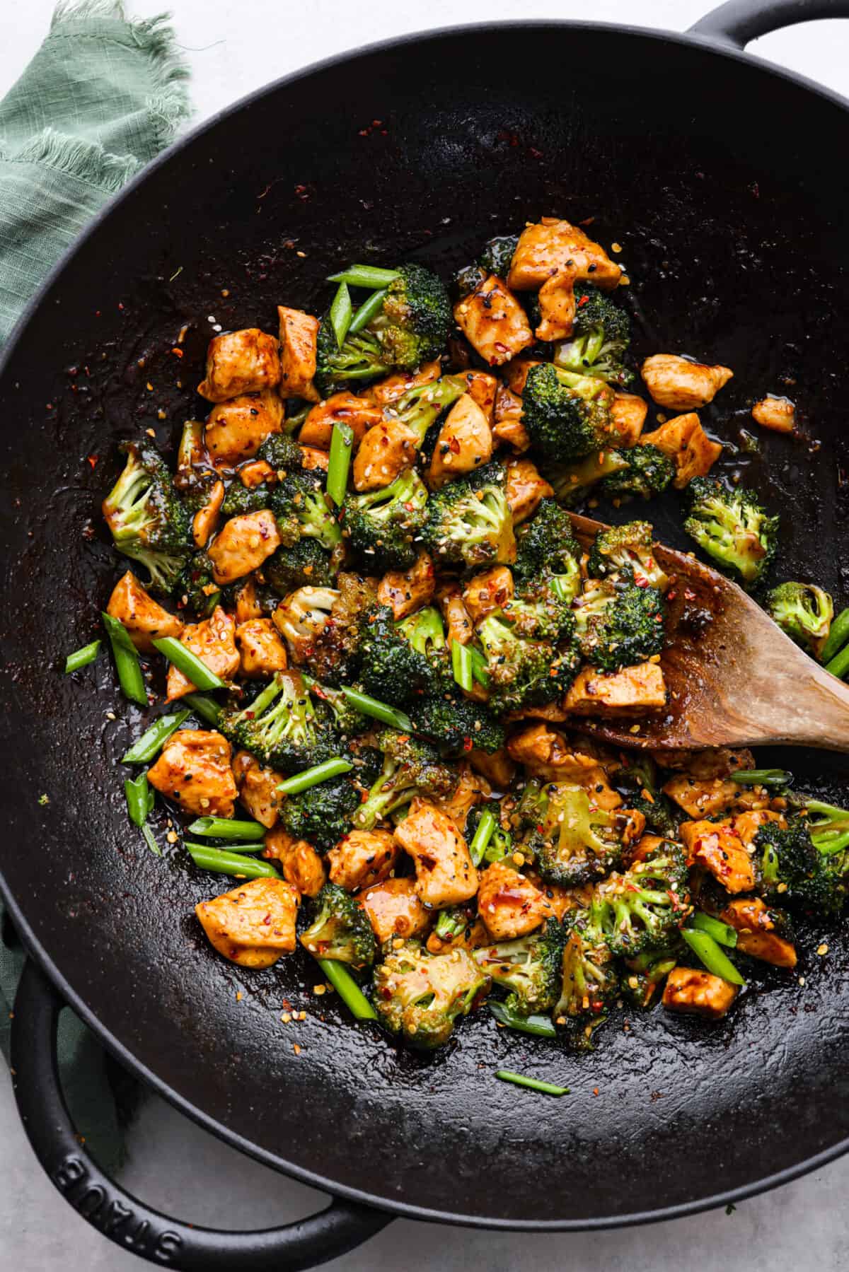This flavorful Chinese Chicken and Broccoli dish is made in just one pan and is ready in less than 30 minutes!ย Small pieces of tender chicken and broccoli florets are cooked in an irresistible sweet and savory sauce. Serve over rice with a sprinkle of sesame seeds and red pepper flakes for an amazing meal! Top-down view of Chinese chicken and broccoli being stir-fried in a wok.