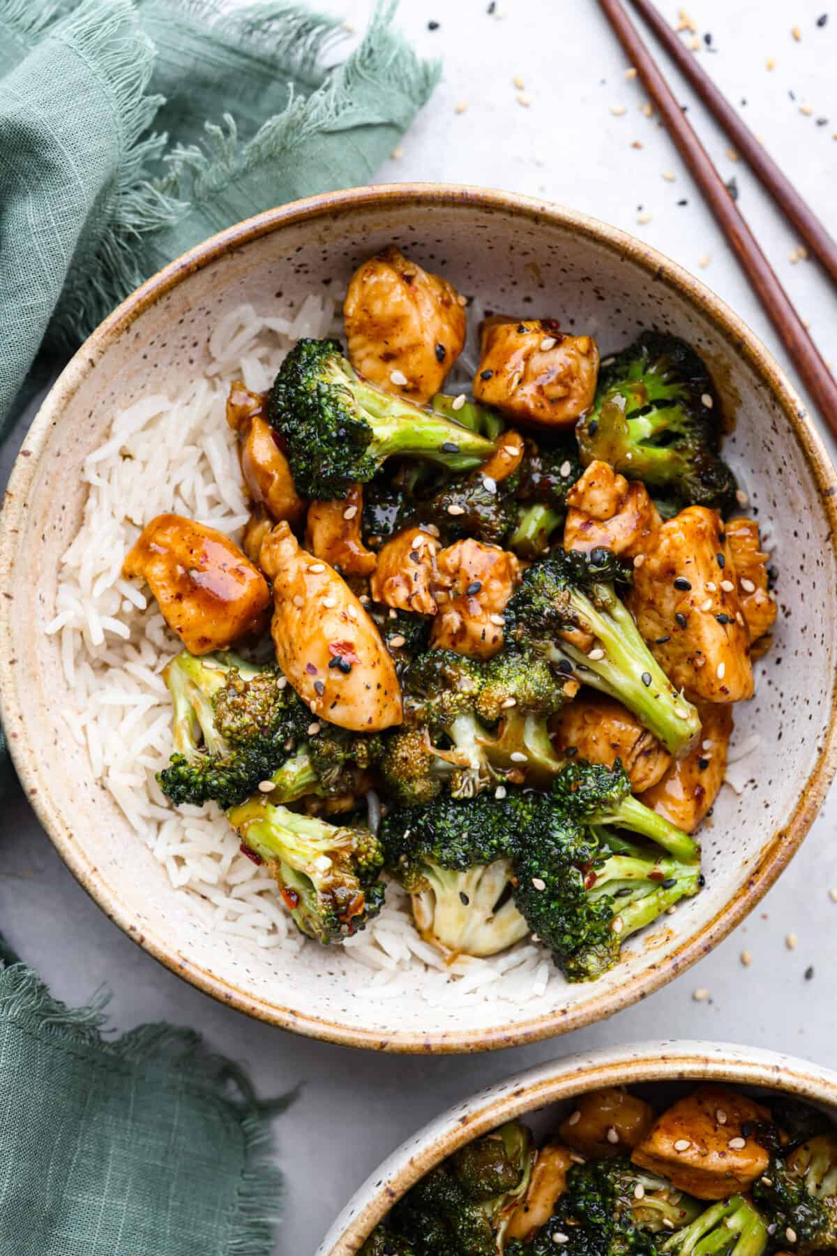 This flavorful Chinese Chicken and Broccoli dish is made in just one pan and is ready in less than 30 minutes!ย Small pieces of tender chicken and broccoli florets are cooked in an irresistible sweet and savory sauce. Serve over rice with a sprinkle of sesame seeds and red pepper flakes for an amazing meal! Chinese chicken and broccoli served in a stoneware bowl with white rice.