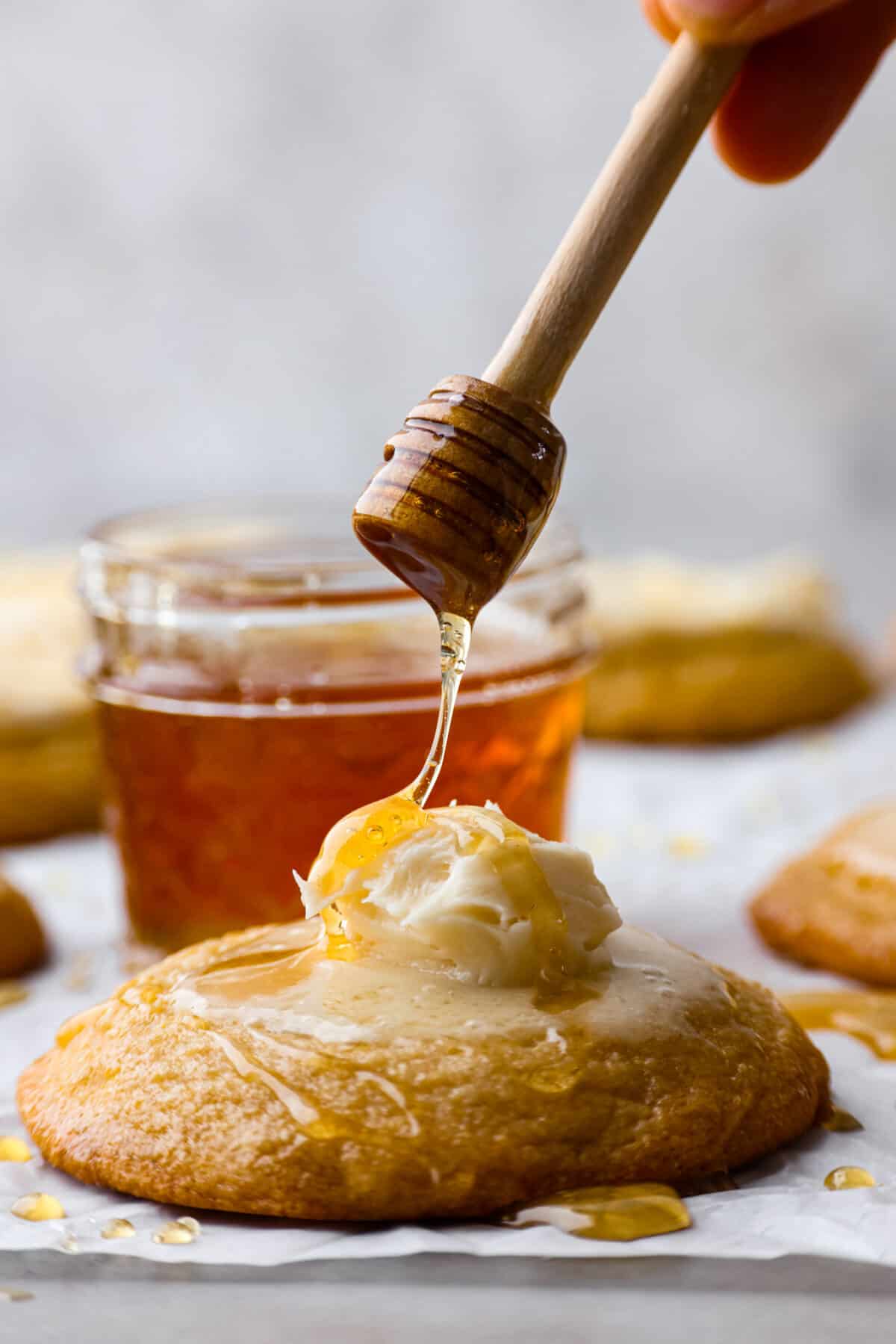 Sweet and buttery cornbread cookies are my favorite cookie Crumbl makes, and I knew I had to recreate this dream cookie. The texture of the cornmeal, the honey butter frosting, and the honey drizzled on top... it all melts in your mouth! Close view of honey drizzling on a cornbread cookie on top of the honey butter frosting.
