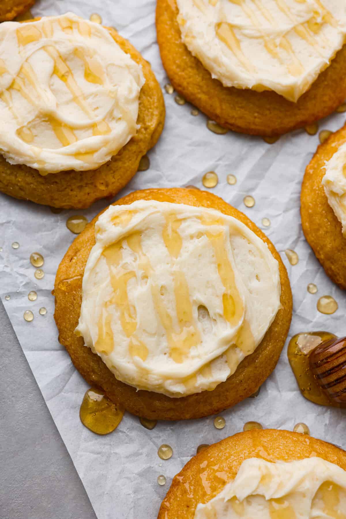 Sweet and buttery cornbread cookies are my favorite cookie Crumbl makes, and I knew I had to recreate this dream cookie. The texture of the cornmeal, the honey butter frosting, and the honey drizzled on top... it all melts in your mouth! Close top view of cornbread cookies with frosting spread on top with a drizzle of honey.