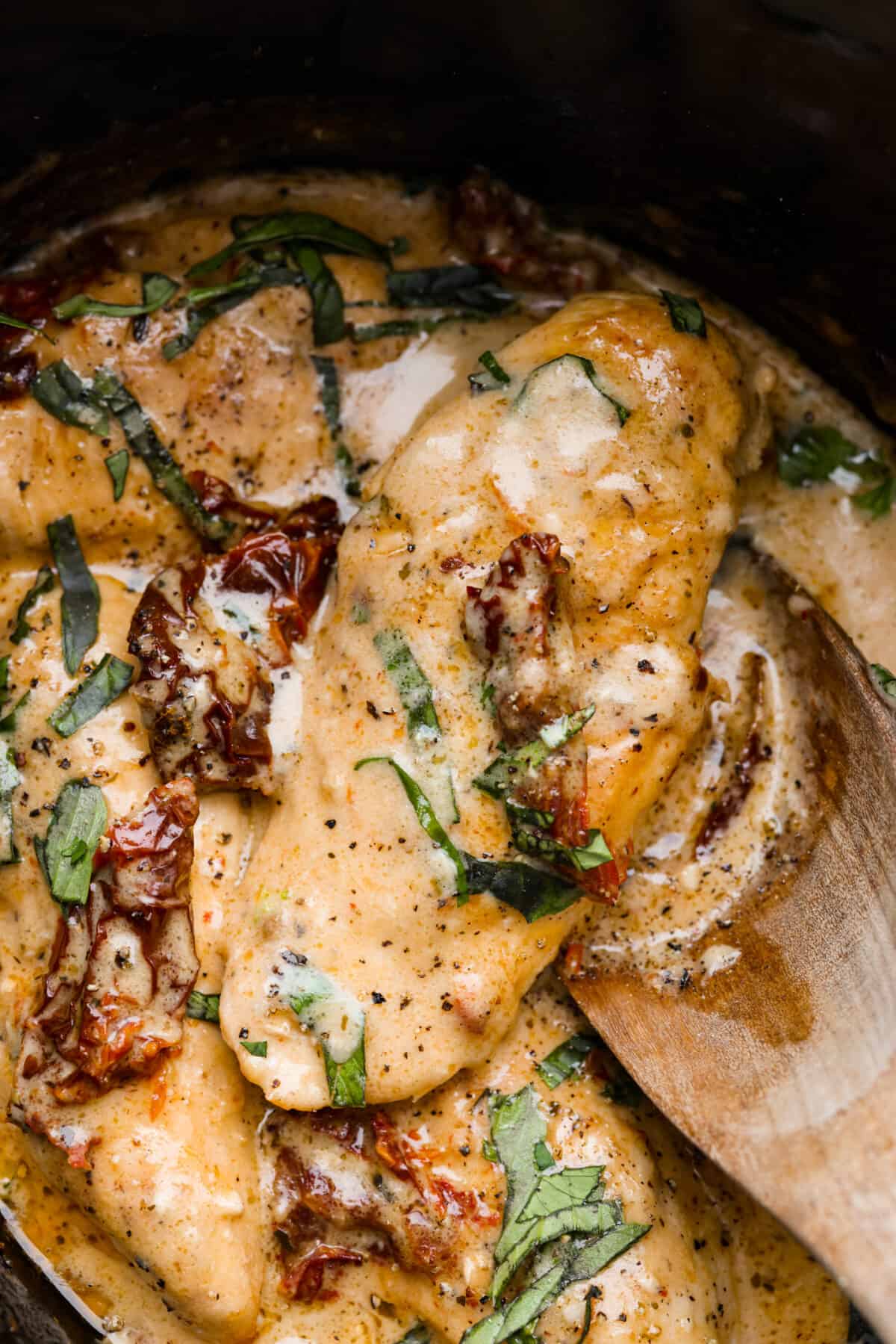 An amazing Tuscan dish made easy in the slow cooker! This Crock Pot Marry Me Chicken is slow cooked to tender perfection and smothered in a creamy, savory sauce made with sun-dried tomatoes and parmesan cheese. The perfect way to win anyone over! Closeup of Crock Pot Marry Me Chicken.