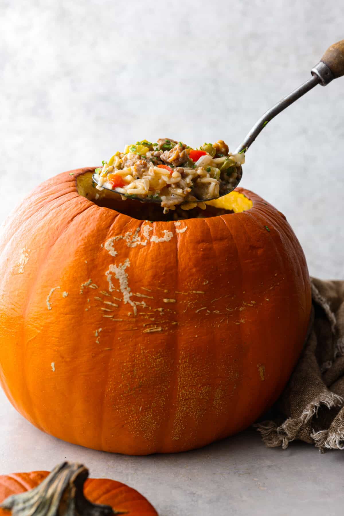 Take your spooky season celebrations up a notch with this festive dinner in a pumpkin! It’s filled with a creamy, savory sausage and rice pilaf that’s sure to be a hit with your family. So delicious, it’s scary. Serving a scoop of dinner in a pumpkin.