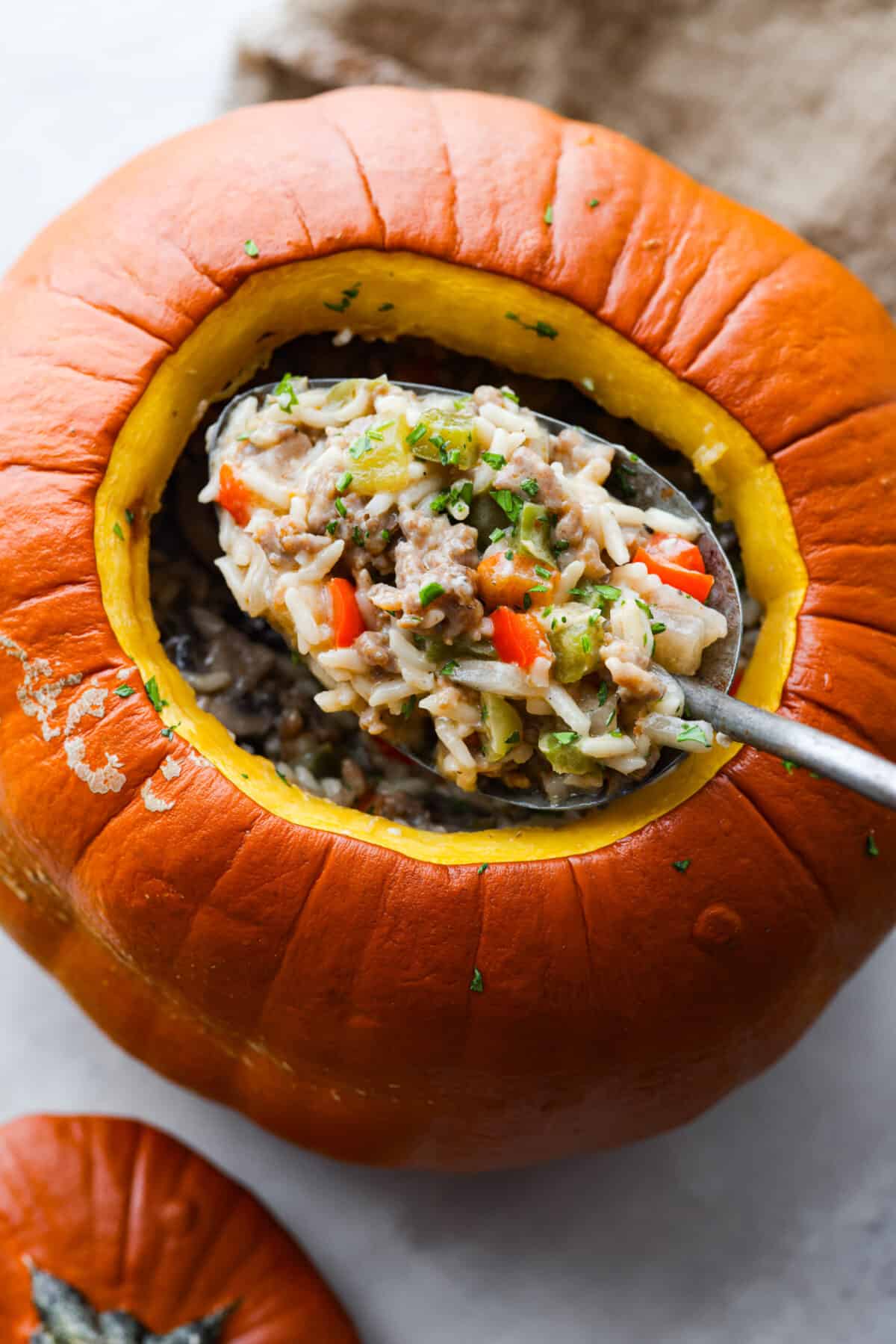 Take your spooky season celebrations up a notch with this festive dinner in a pumpkin! It’s filled with a creamy, savory sausage and rice pilaf that’s sure to be a hit with your family. So delicious, it’s scary. Closeup of dinner in a pumpkin.