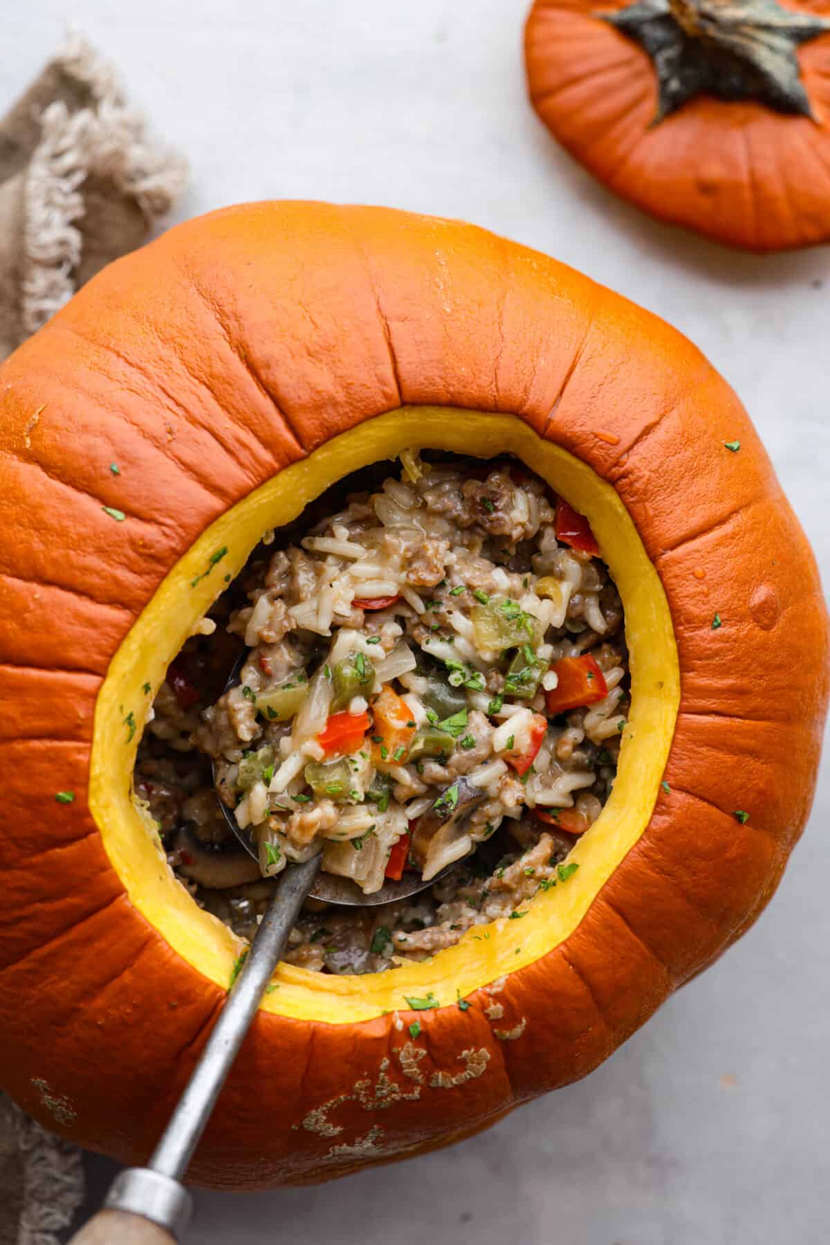 Take your spooky season celebrations up a notch with this festive dinner in a pumpkin! It’s filled with a creamy, savory sausage and rice pilaf that’s sure to be a hit with your family. So delicious, it’s scary. Top-down view of a pumpkin that has been hollowed out and filled with sausage, rice, and vegetables.