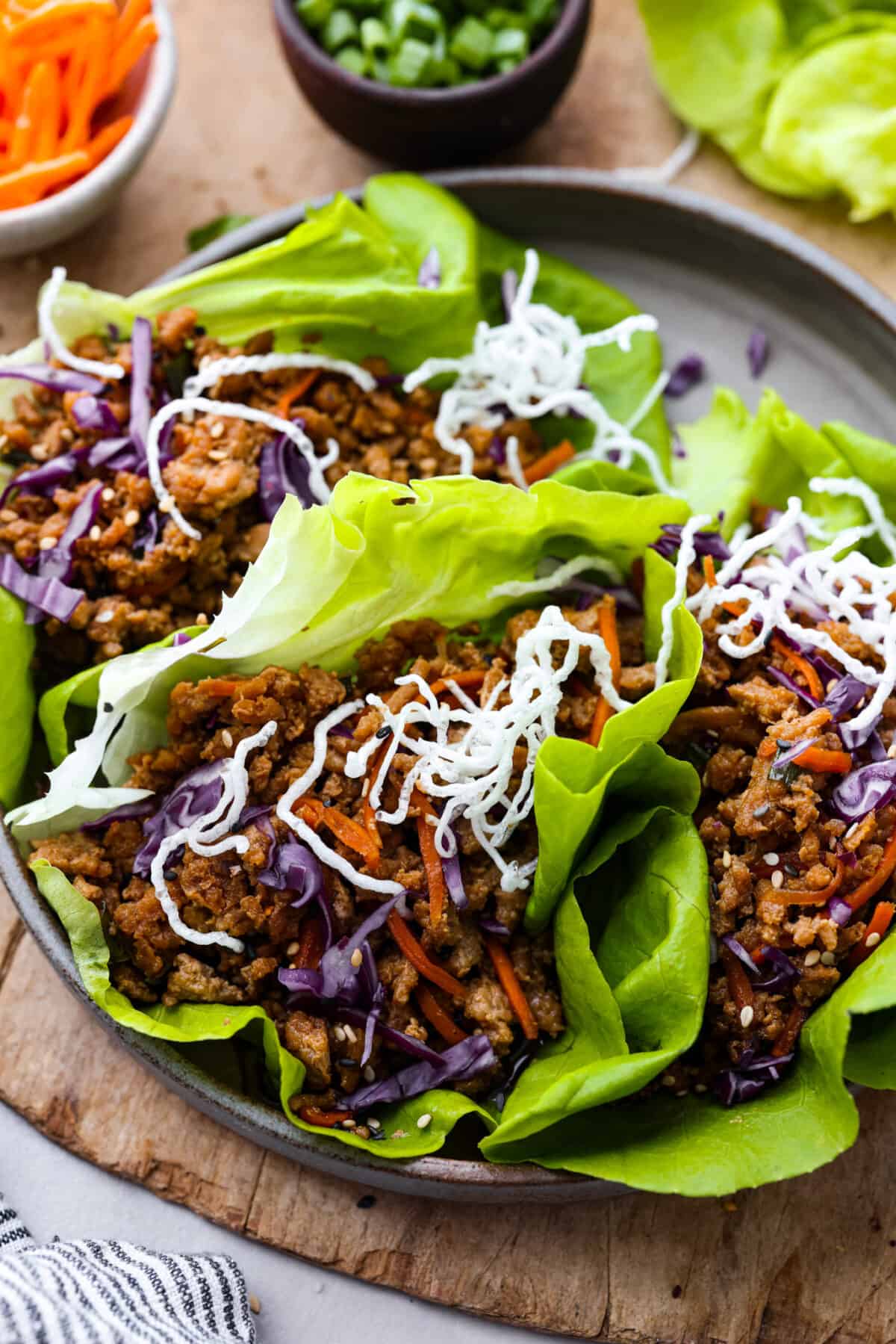 Healthy and easy, these Chicken Lettuce Wraps are so fresh and delicious! They're ready in under 30 minutes with a juicy chicken filling and crispy butterhead lettuce. Closeup of 3 chicken lettuce wraps, topped with rice noodles.