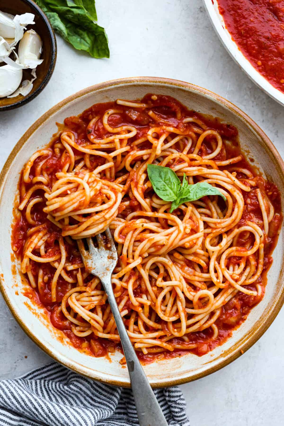After testing this Homemade Marinara Sauce recipe, I'm happy to say that this is for sure the best version. You can quickly make this in 15 minutes, but I highly recommend letting it simmer and stew on the stove top. This lets the flavors meld and enhance as they cook. Plate of spaghetti noodles smothered in homemade marinara sauce garnished with a sprig of fresh basil.