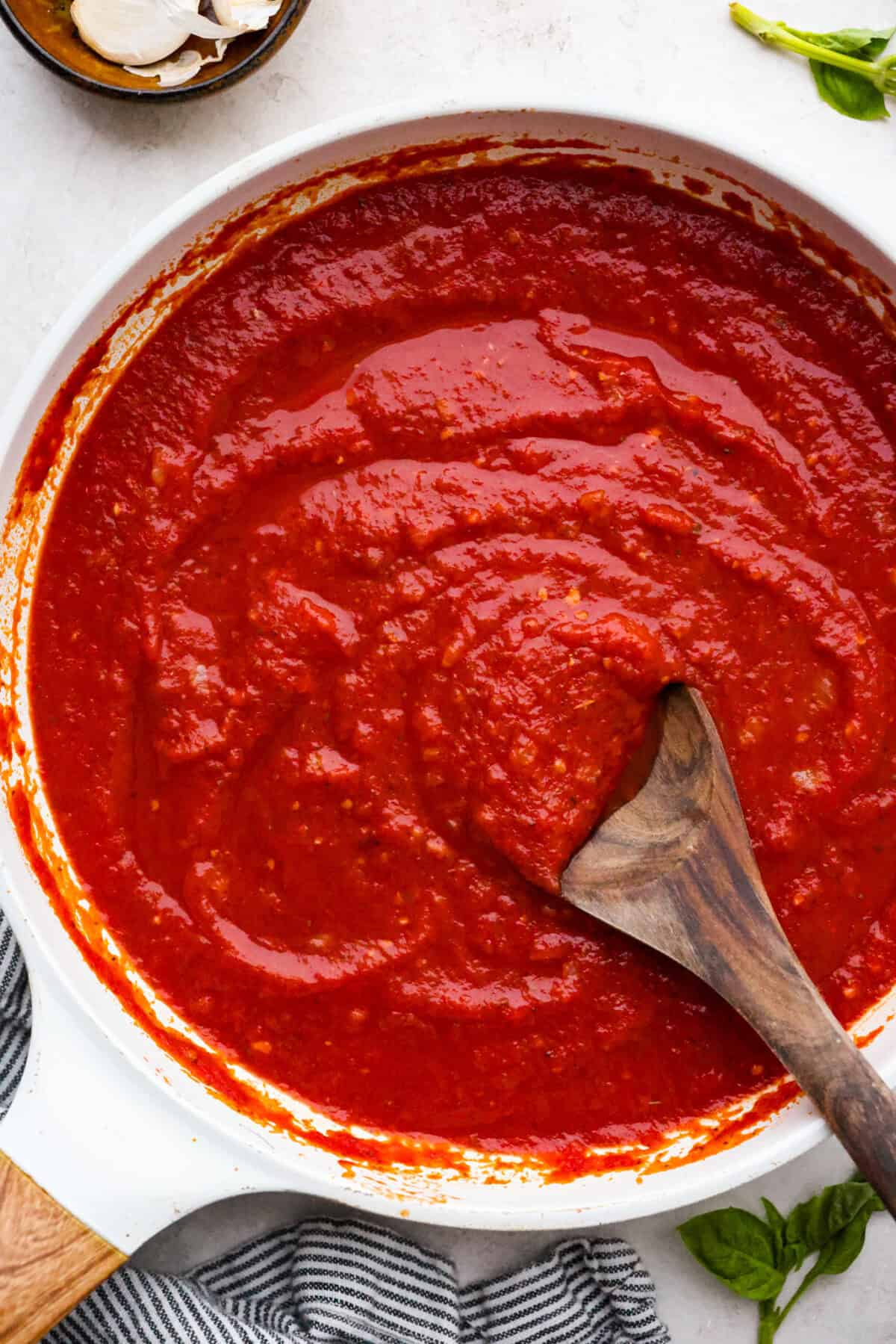 After re-testing this Homemade Marinara Sauce, I can confidently say itโs the BEST! You can make it in 15 minutes, but letting it simmer makes the flavors even better! Top down shot of homemade marinara sauce in a saucepan with wooden serving spoon.