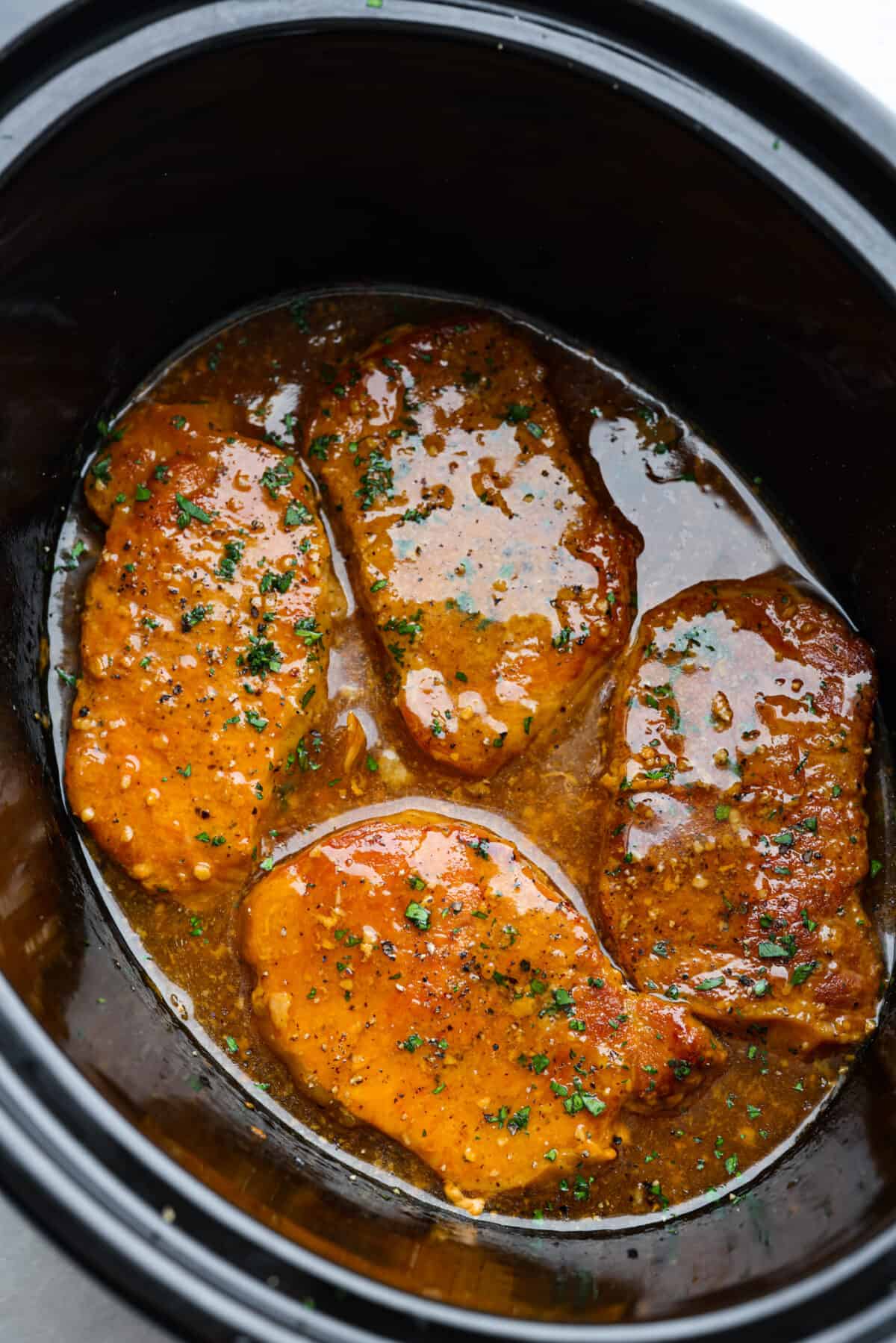 These slow cooker honey garlic pork chops are incredibly tender, they practically melt in your mouth! Cooked in a sweet and savory sauce, you won't be able to stop after one bite. Cooked honey garlic pork chops in the slow cooker.