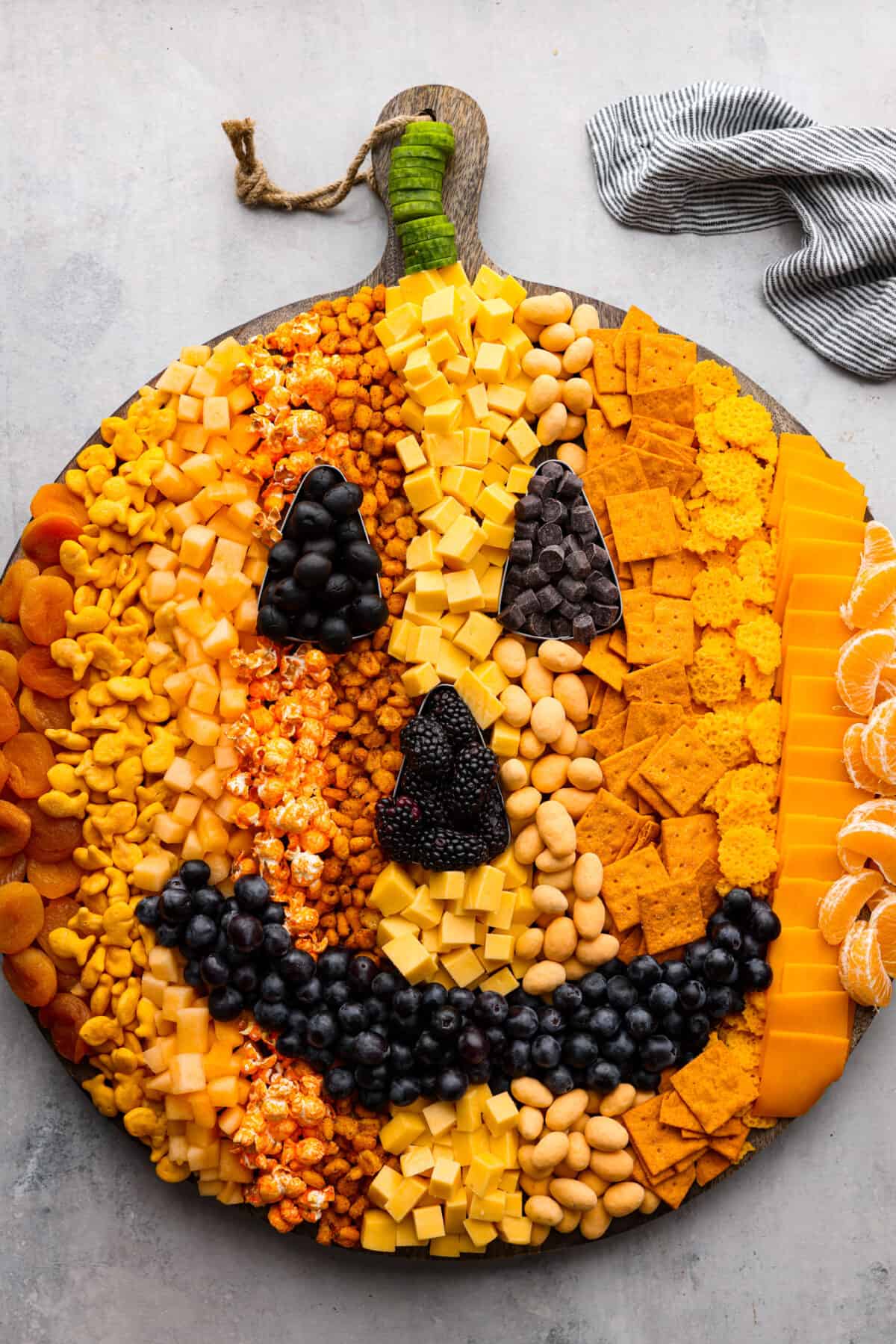 Halloween is the BEST time to get creative and have fun with your food! Gather all things orange and bring this pumpkin charcuterie board to your next fall get-together. Fill your board to look like a Jack-o-lantern; it will be the talk of the party! Top view of a pumpkin charcuterie board.
