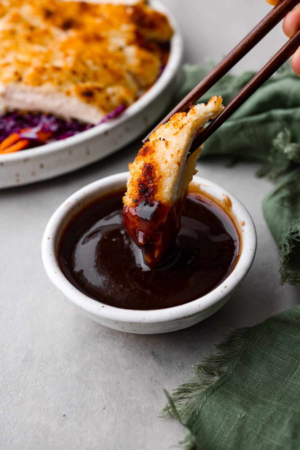 Katsu sauce is a thick and glossy ketchup-based sauce that's perfect for dipping fried foods in! A staple in Japanese and Hawaiian cuisine, you're going to love having this on hand in your kitchen. Dipping a piece of breaded chicken in the sauce.