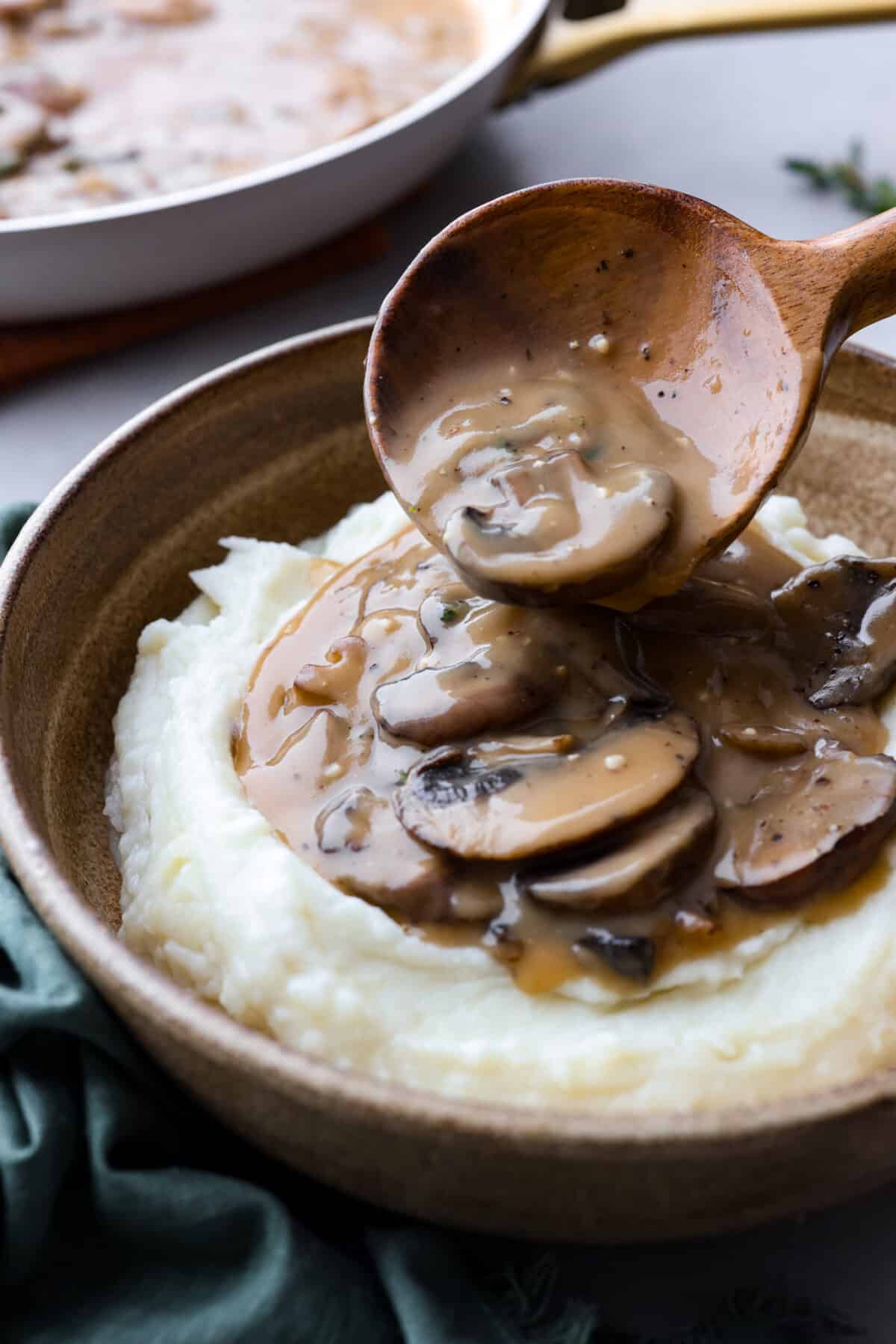 Savory Mushroom Gravyย is rich, flavorful, and the perfect topping for steak, pork, chicken, or mashed potatoes. It's easy to make and ready in just 20 minutes! Mushroom gravy being poured over a serving of mashed potatoes.