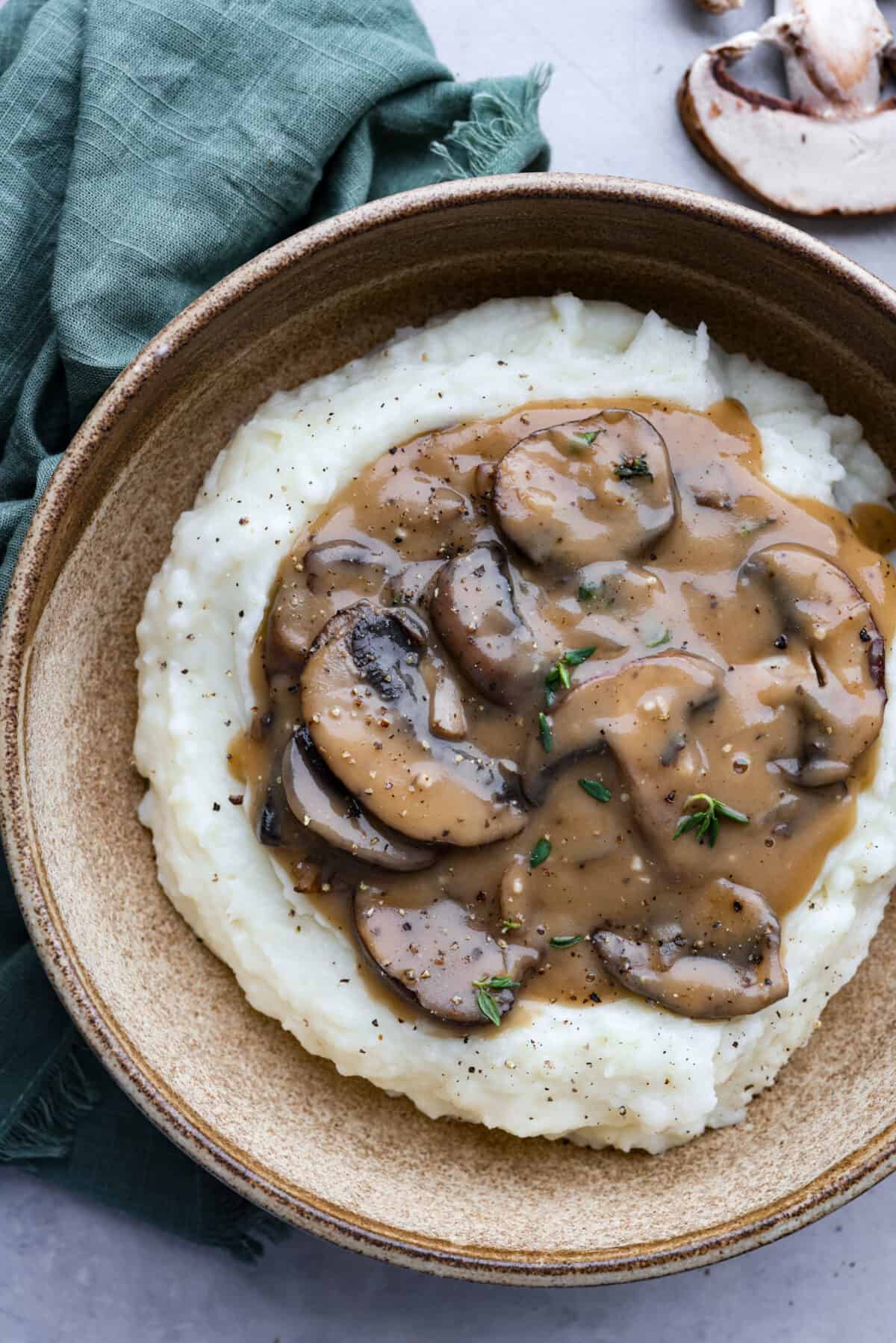 Savory Mushroom Gravyย is rich, flavorful, and the perfect topping for steak, pork, chicken, or mashed potatoes. It's easy to make and ready in just 20 minutes! Top-down view of mashed potatoes served in a brown bowl.