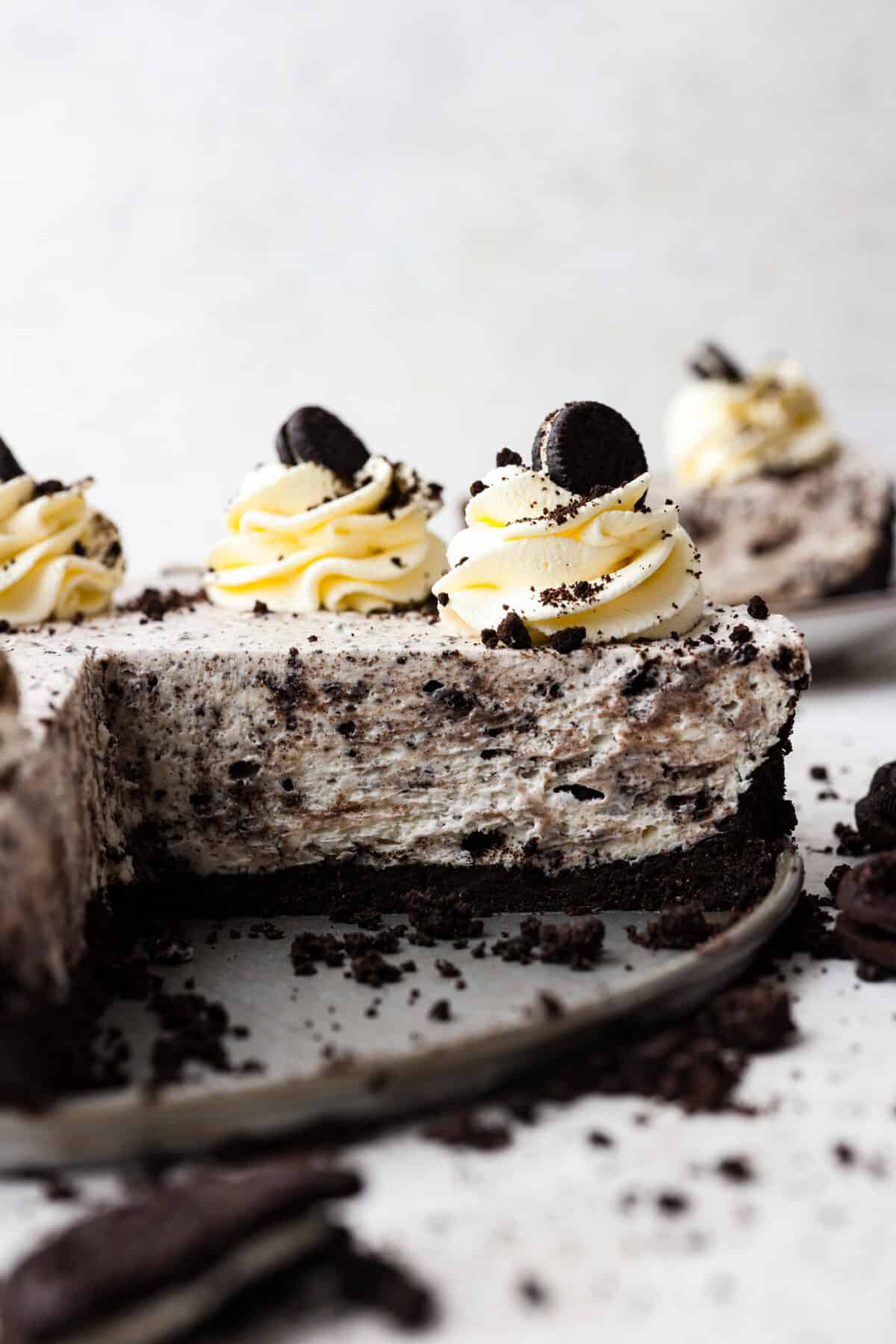 Indulge in pure dessert delight with this no-bake Oreo cheesecake! It has a creamy filling packed with crushed Oreos on a crust made of even more Oreos—talk about dreamy! And the best part? It's a breeze to whip up, no need to turn on your oven! No Bake Oreo Cheesecake with a slice cut out of it.